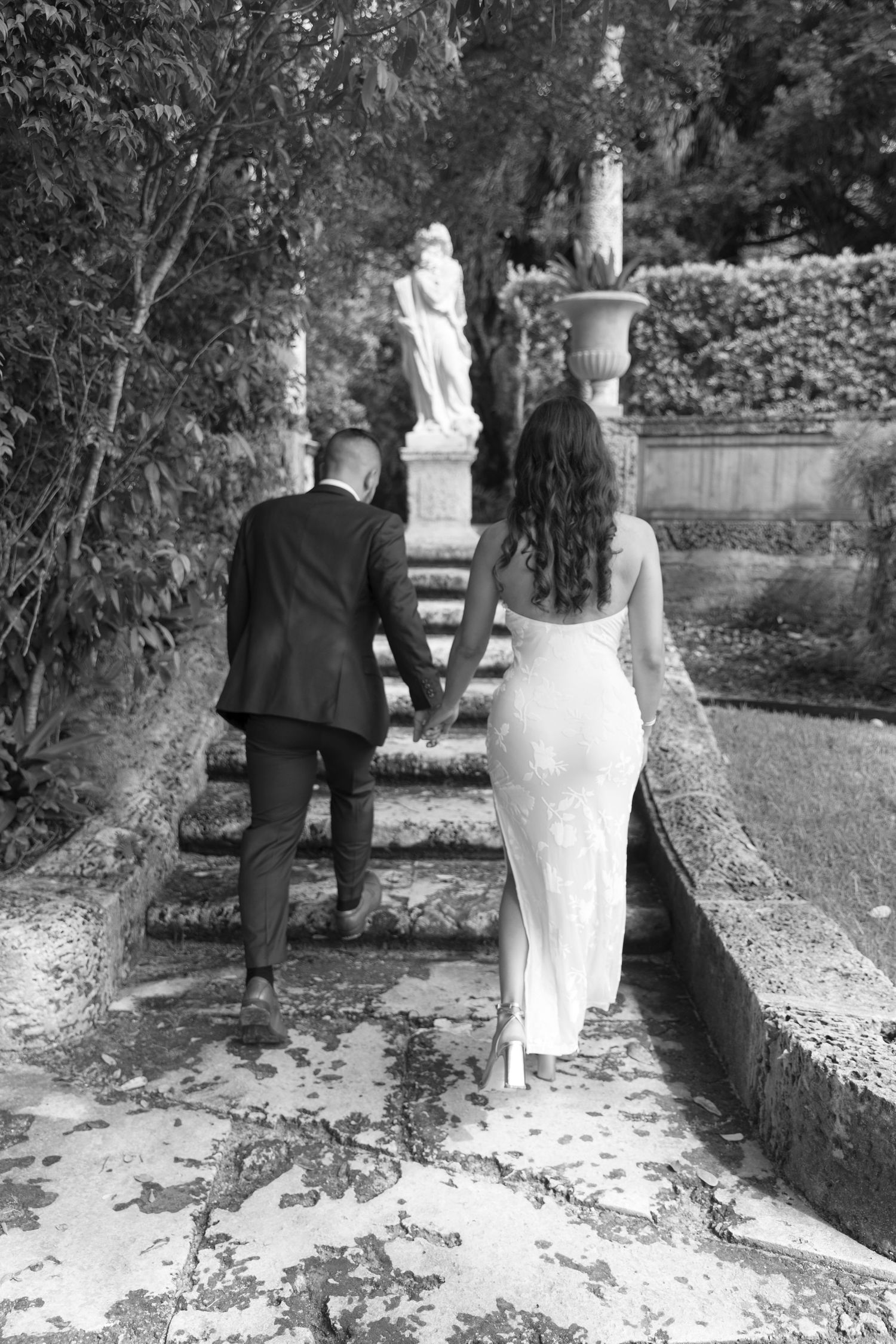 A black and white photograph showing people walking along a garden path.