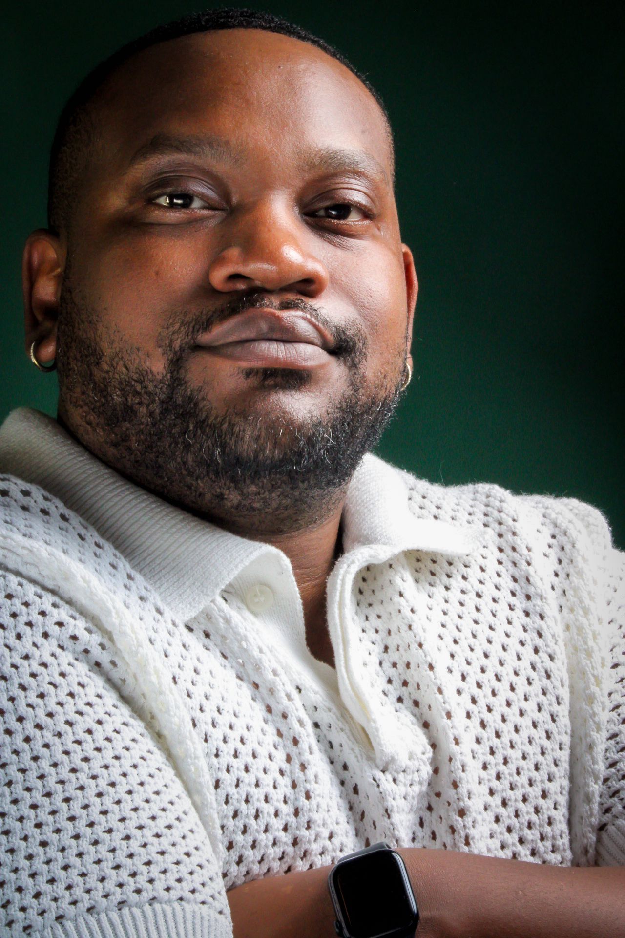 A person in a black graphic t-shirt and white pants poses confidently against a light background.