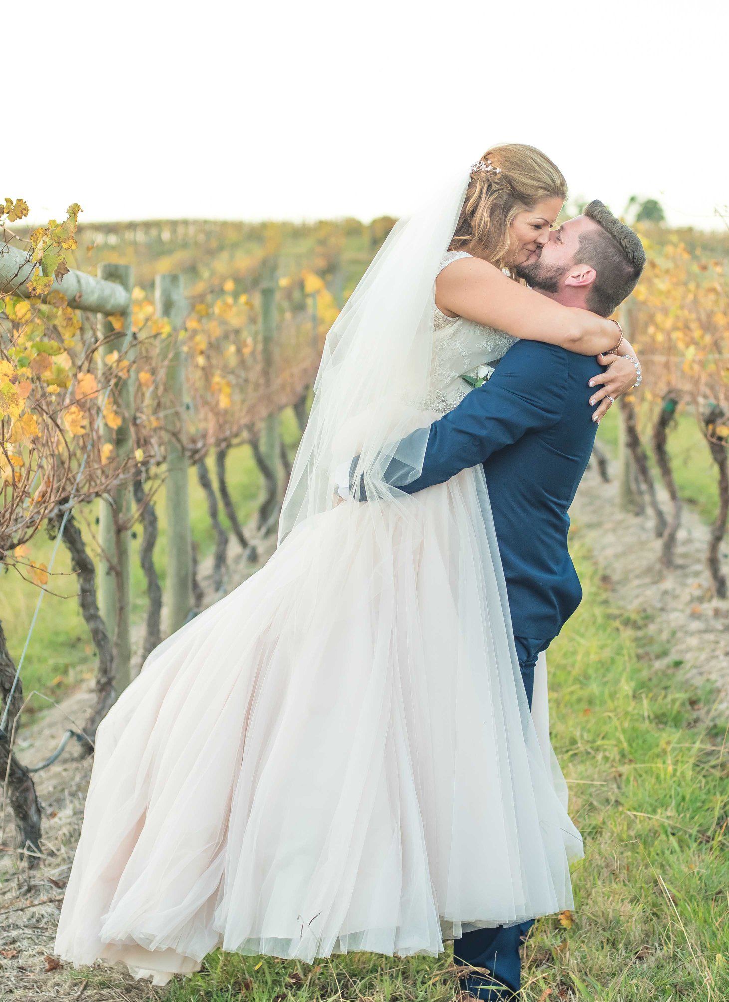 a newly married couple hugging in the vineyard