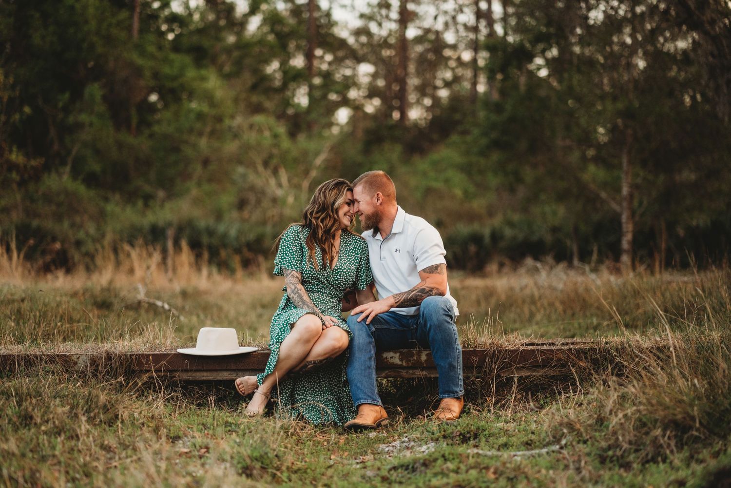 A couple shares a tender moment while sitting on wooden steps in a rustic outdoor setting.