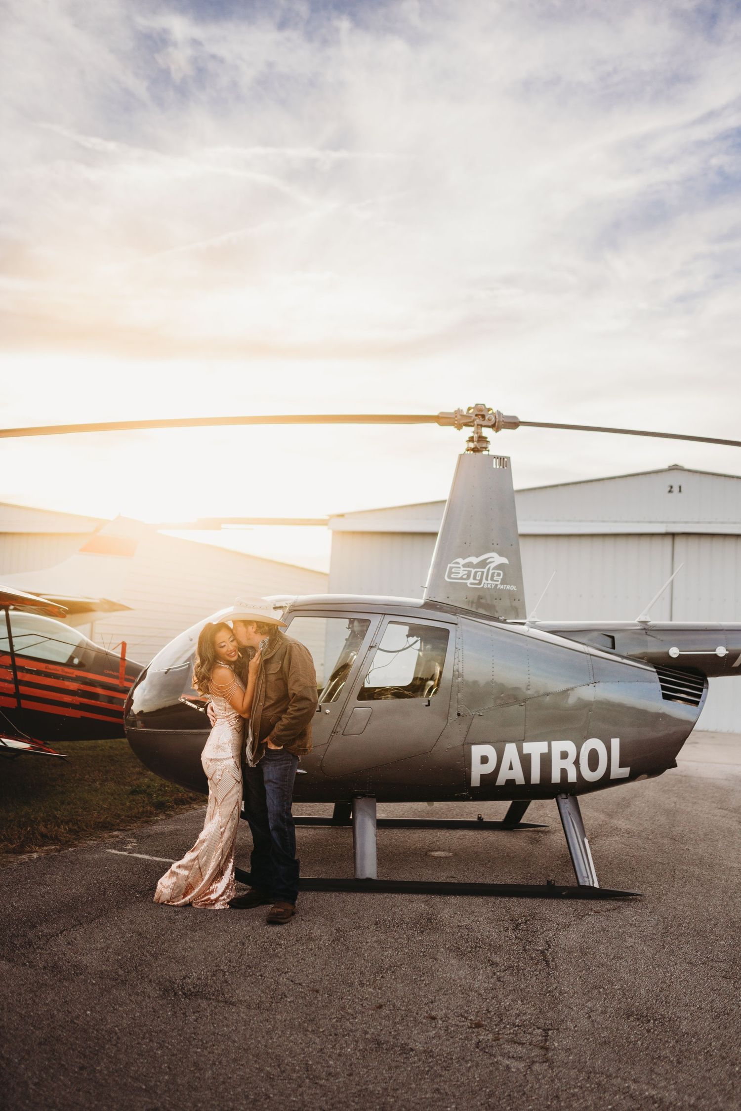 A romantic moment shared beside a patrol helicopter during sunset.