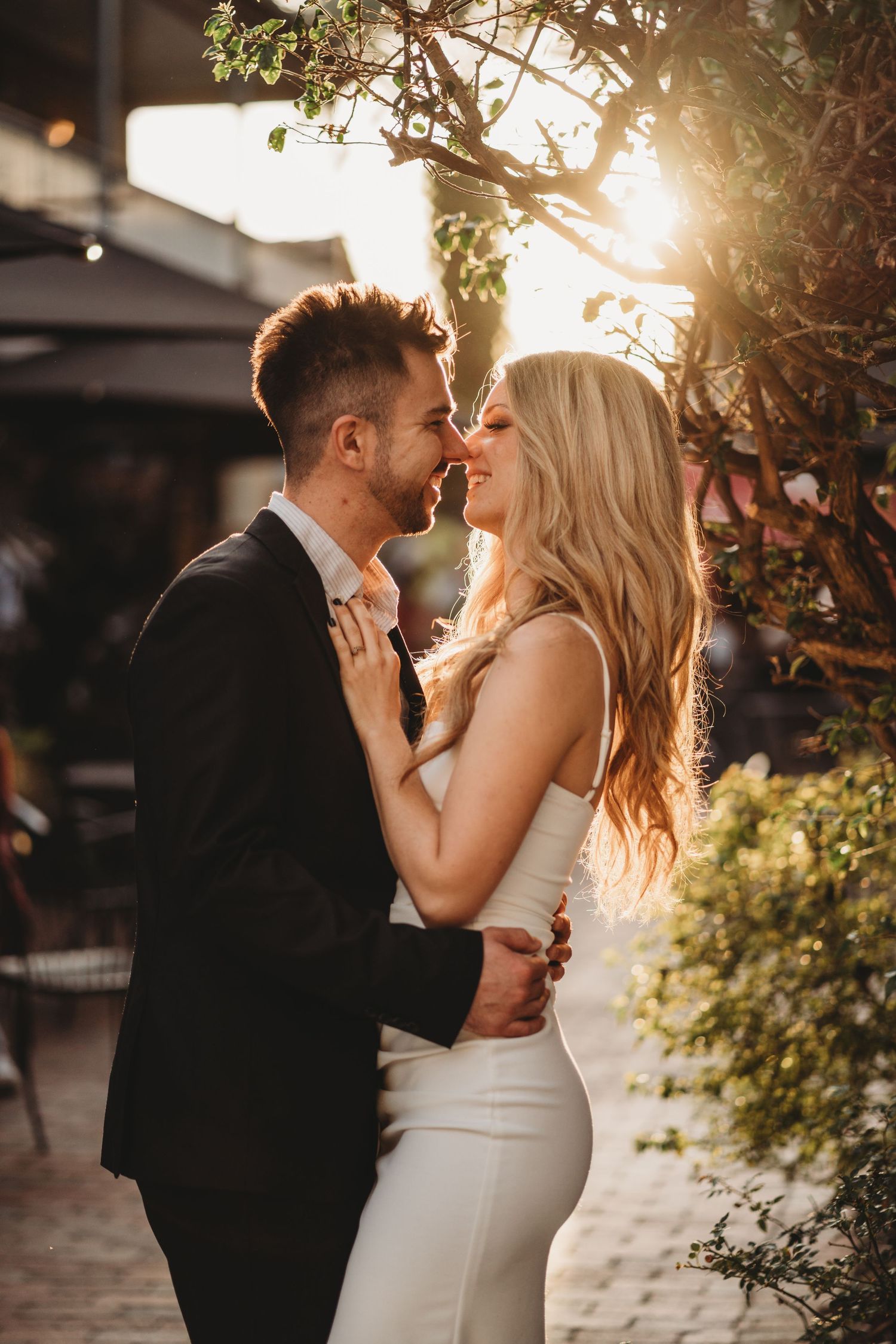 Intimate sunset portrait of couple embracing against natural foliage backdrop.