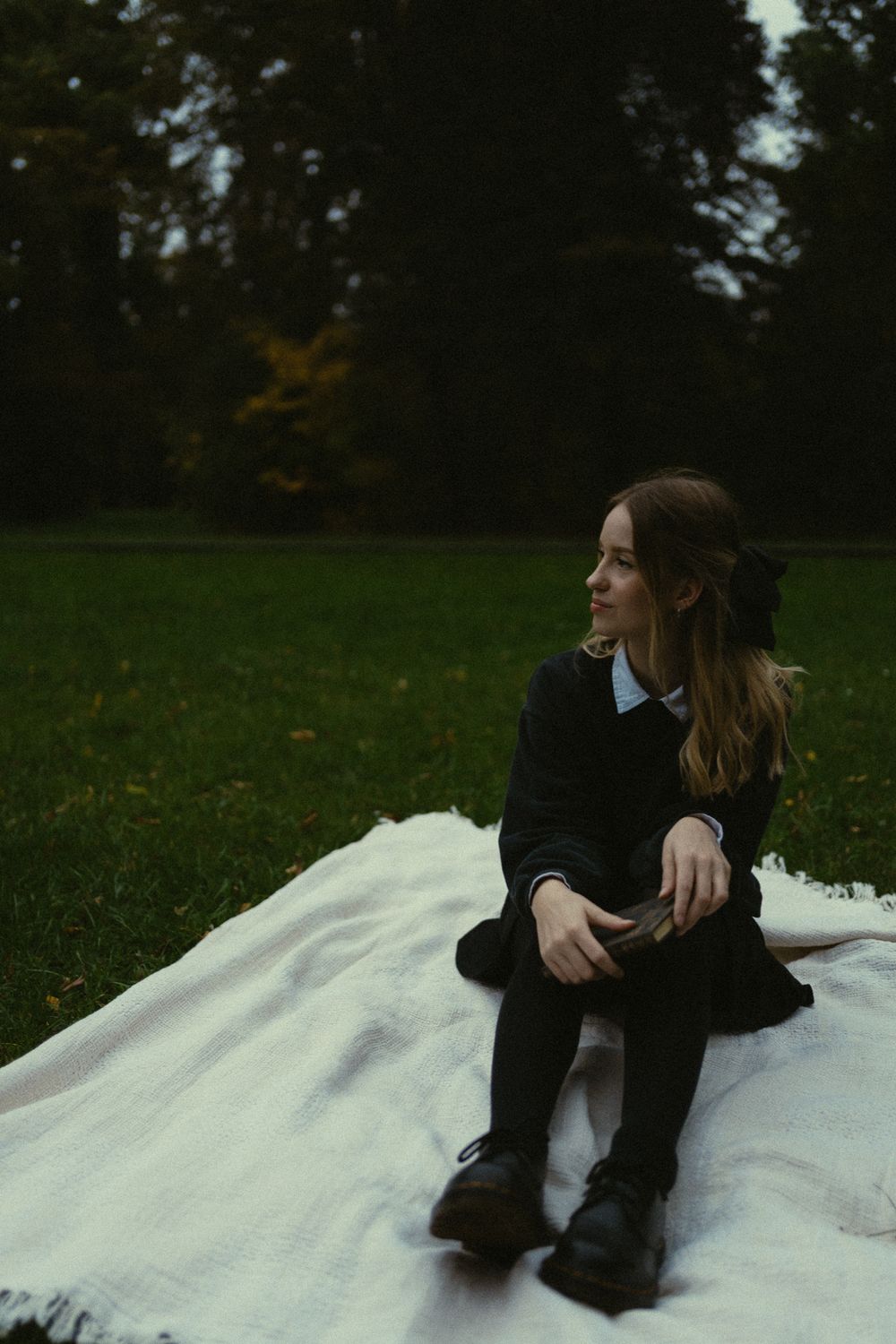 Portrait Fotografie einer Frau auf Decke sitzend und Blick durch den Park streifend, Buch in der Hand im Großen Garten Dresden
