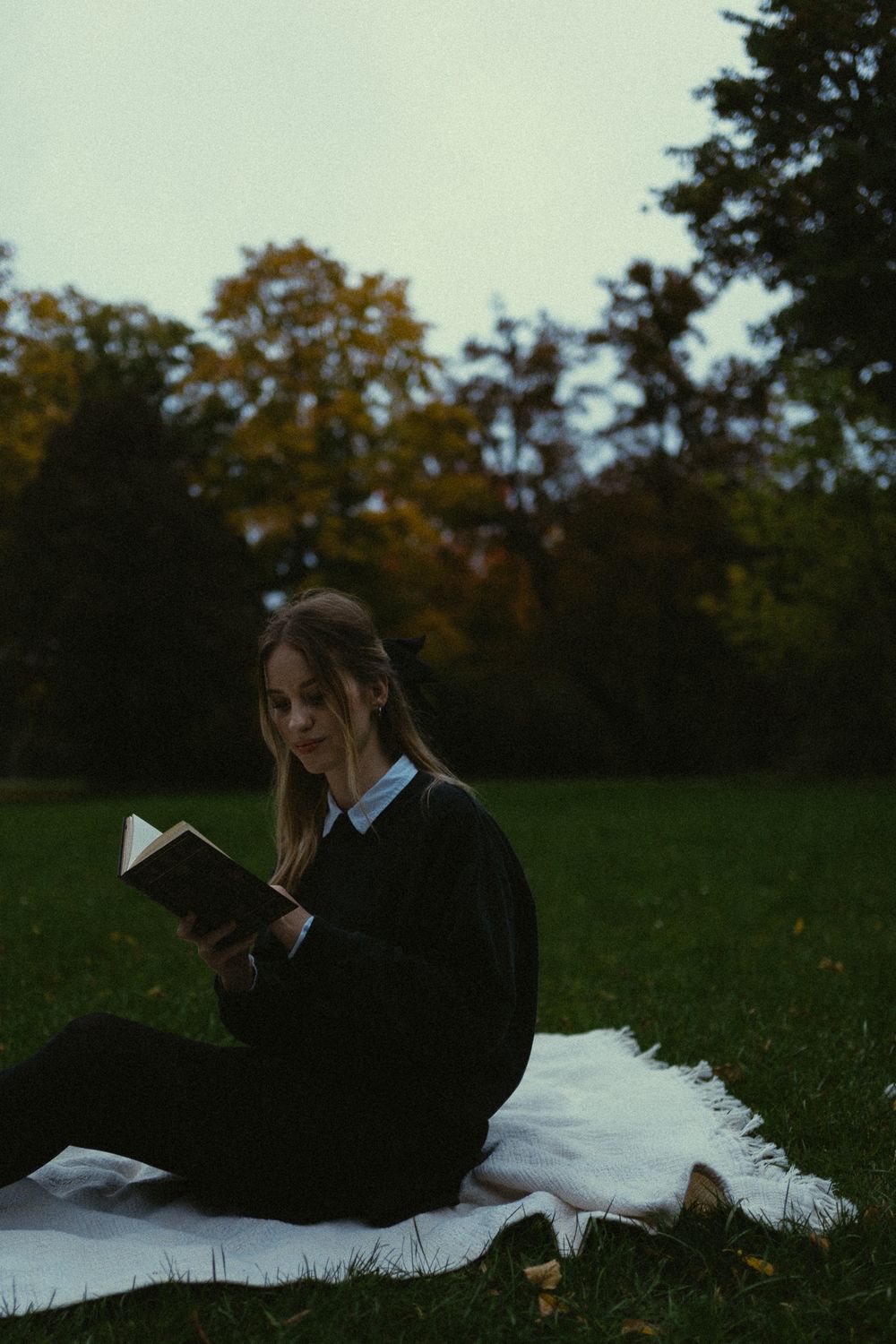 Portraitfotoshooting - Junge Frau im Vintage Look liest im Sitzen auf weißer Decke ein Buch im Großen Garten in Dresden