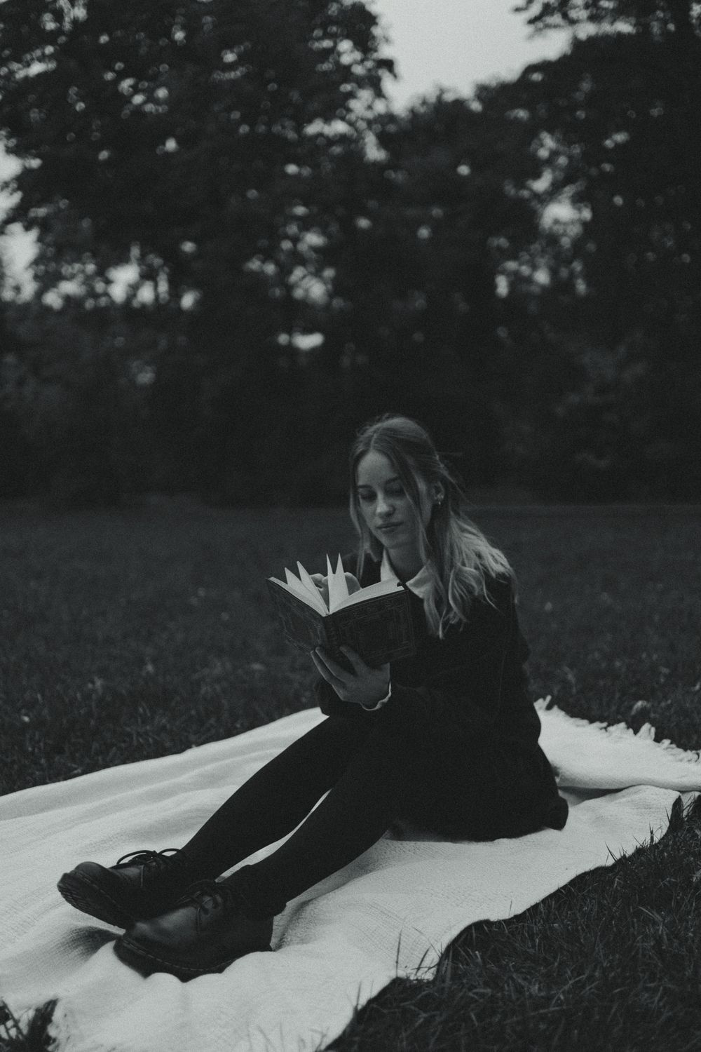 Zum Sonnenuntergang liest eine junge Frau auf Decke ein Buch im Grünen im Großen Garten in Dresden - Portrait Fotoshooting im Vintage Stil