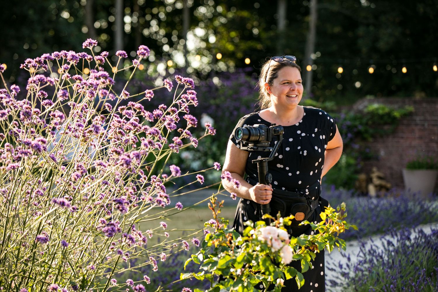 A photographer lies in tall grass with camera equipment.