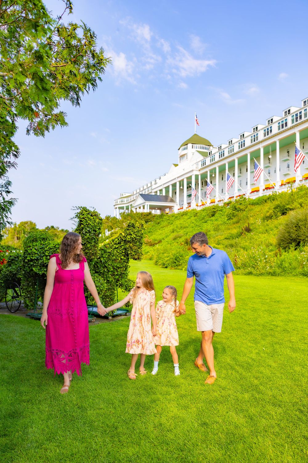 Group walking up a lush green hillside on a sunny day at Grand Hotel on Mackinac Island.