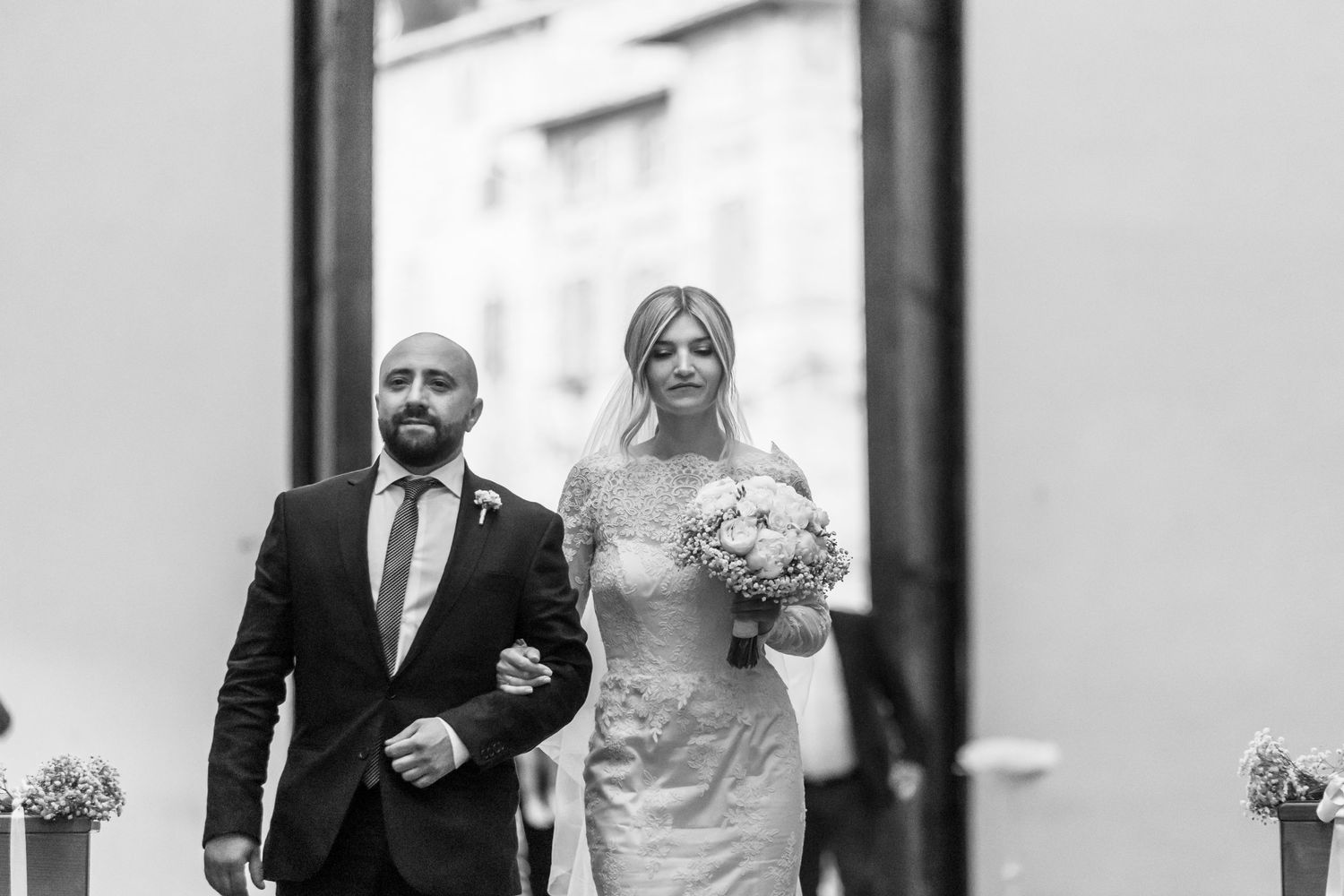 Elegant couple walking arm in arm at their wedding in black and white.