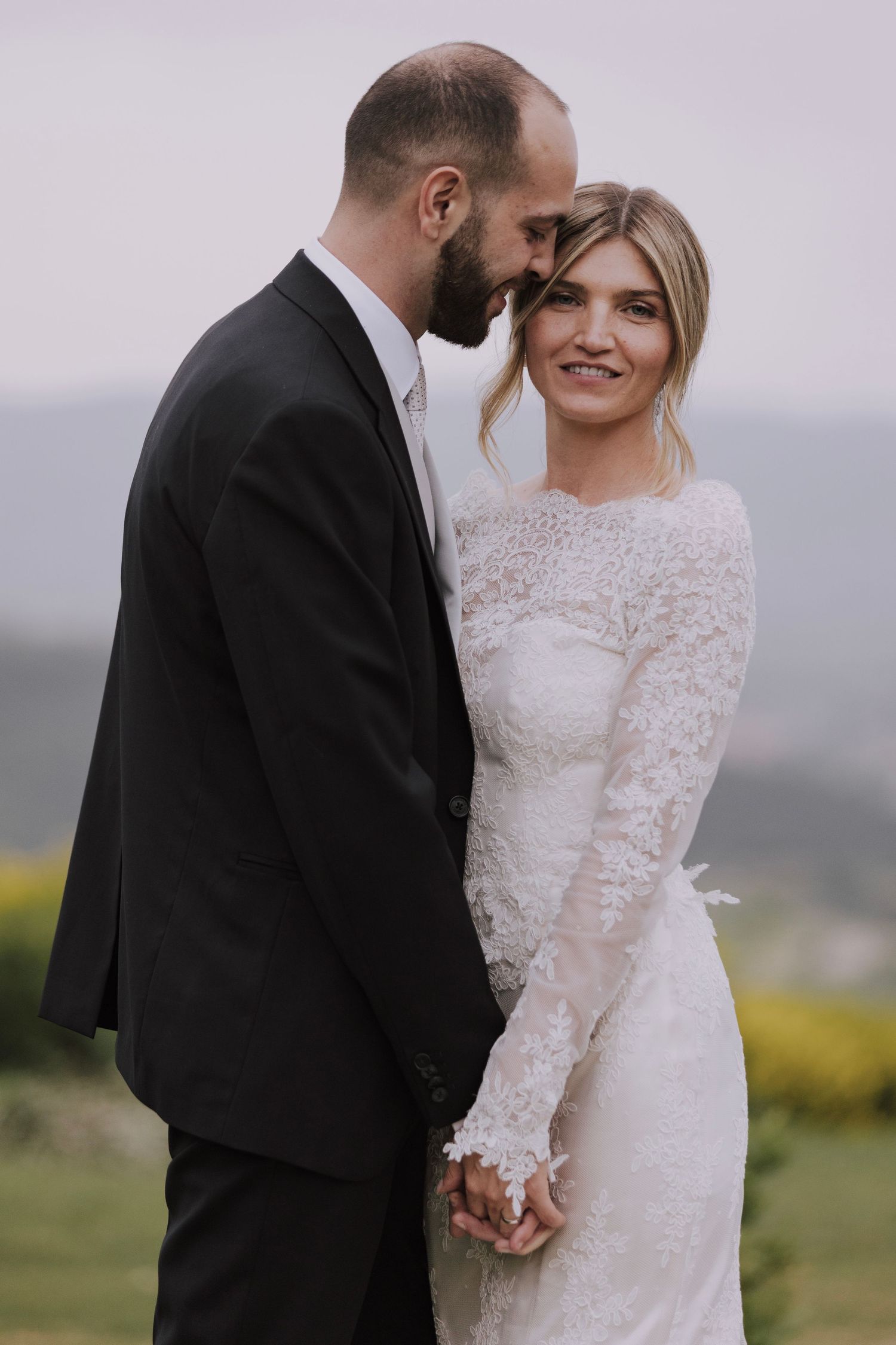 Intimate wedding portrait captured against misty mountain landscape.