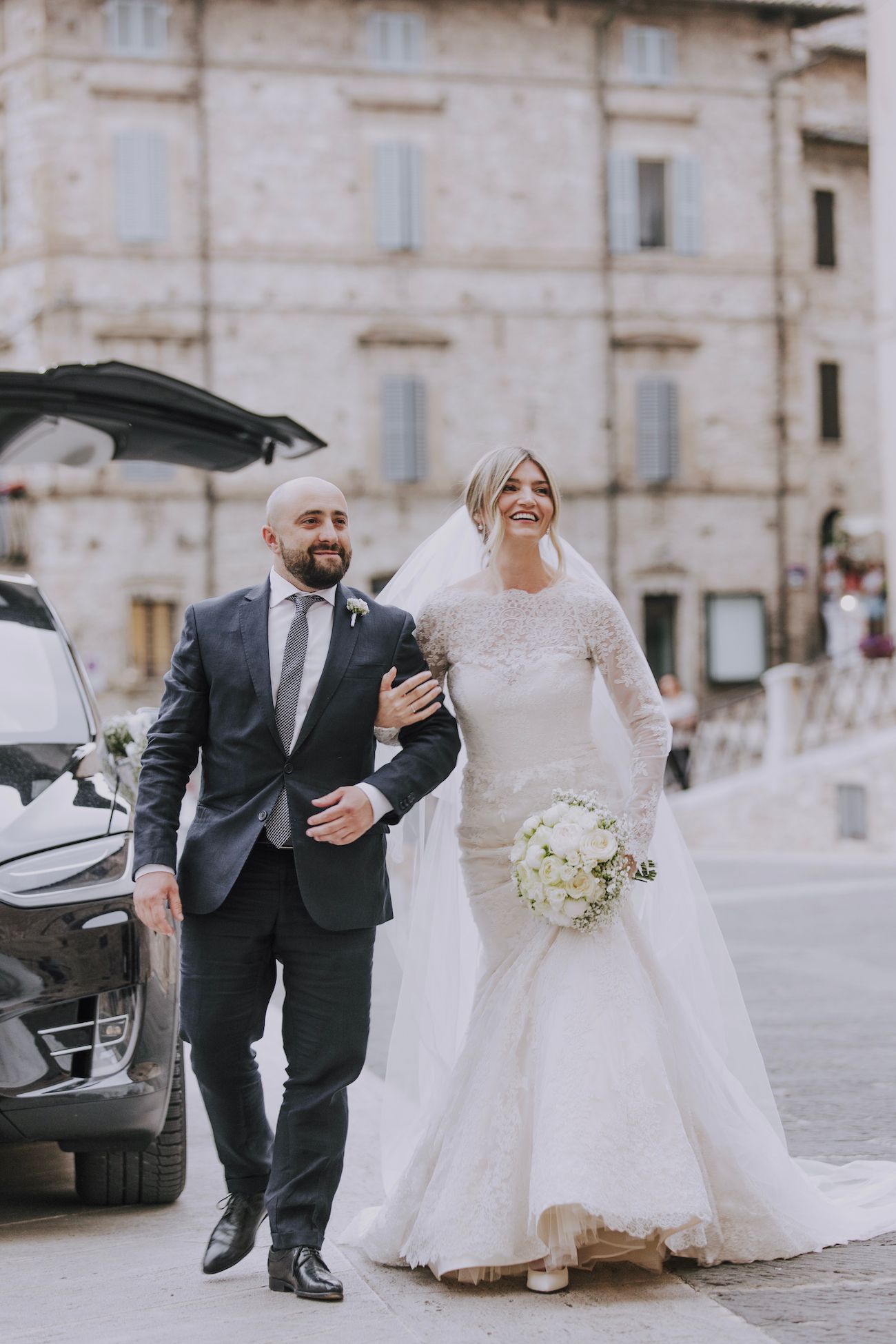 Joyful wedding couple walking together outside historic building.