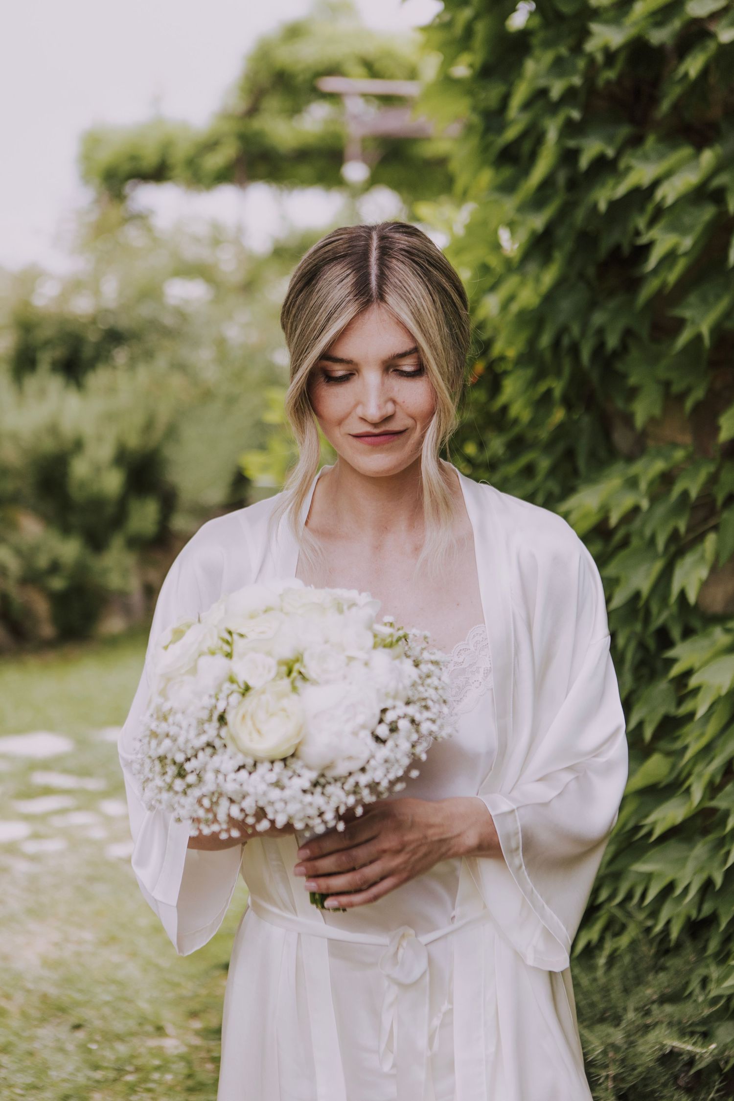 Bridal portrait with white bouquet against green ivy backdrop.
