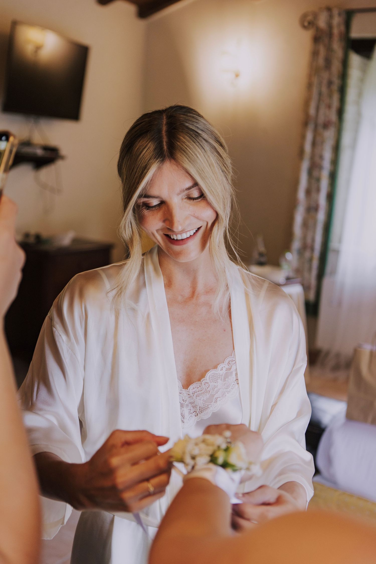 Morning wedding preparation moment in a cozy room with natural light.