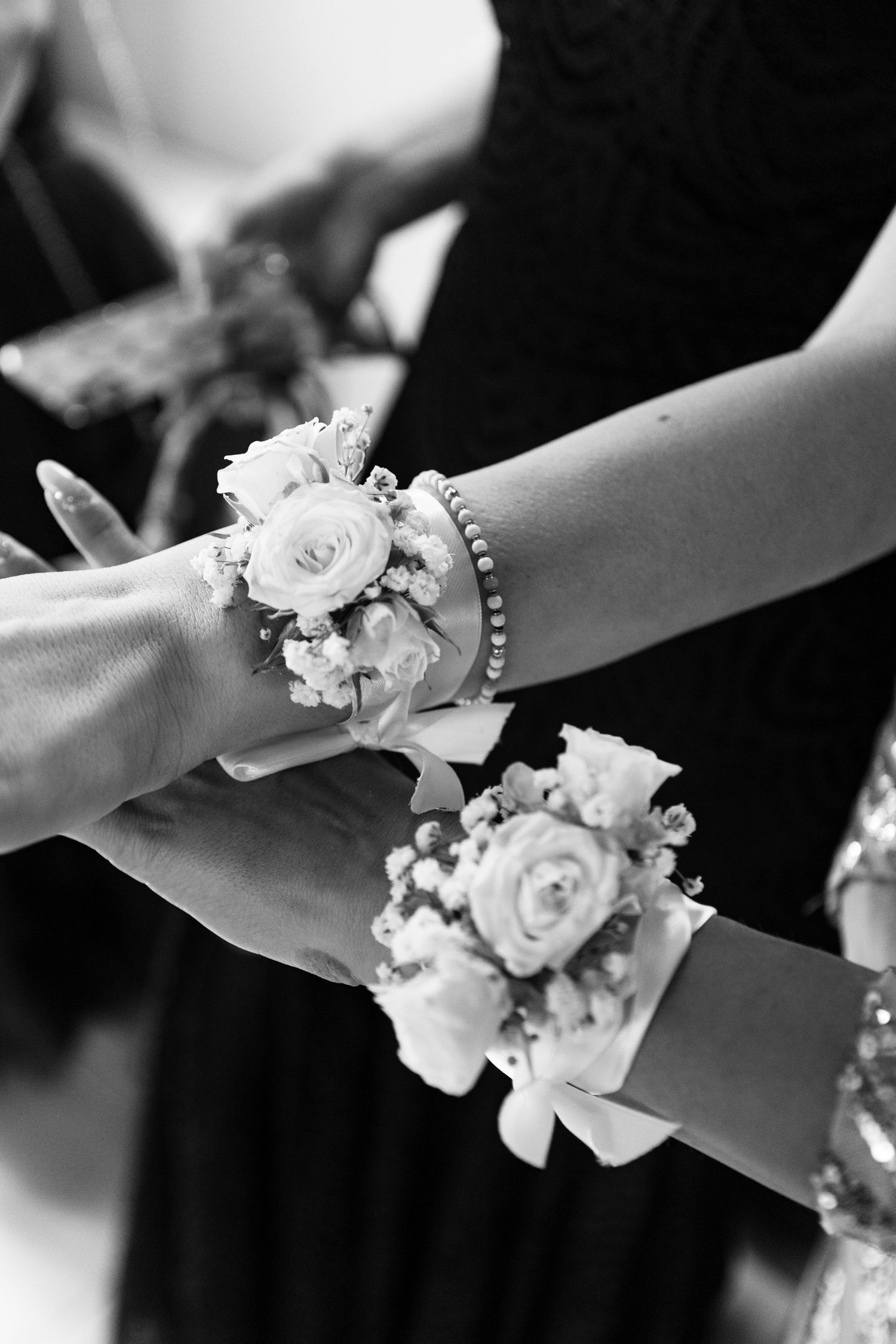 Delicate white floral corsages on wrists at a wedding ceremony.