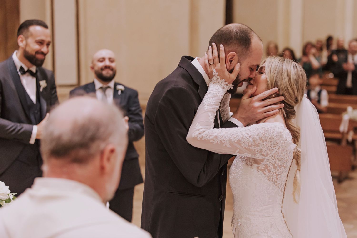 An emotional wedding ceremony kiss in an elegant church interior.