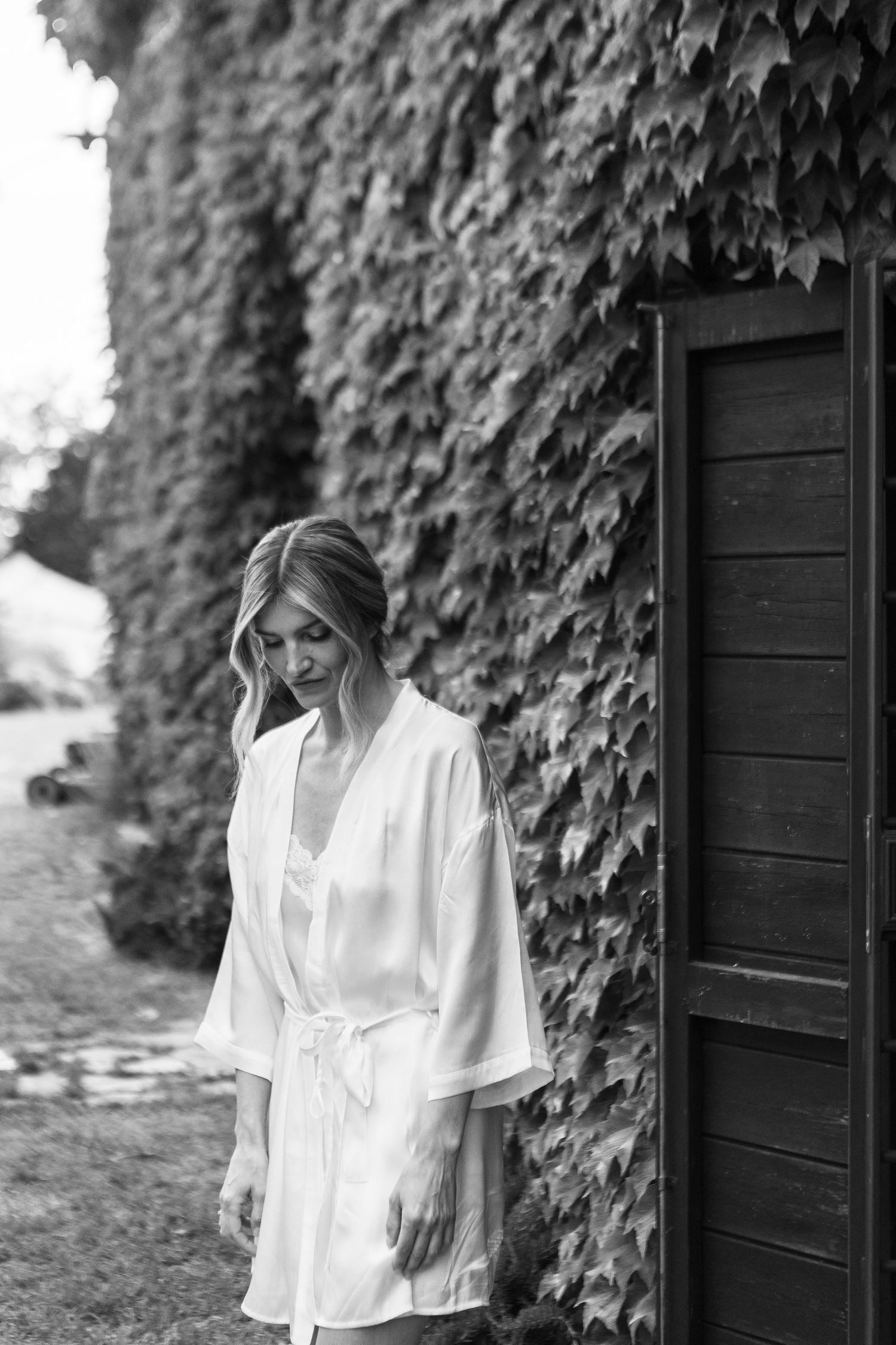 Black and white portrait against ivy-covered wall.