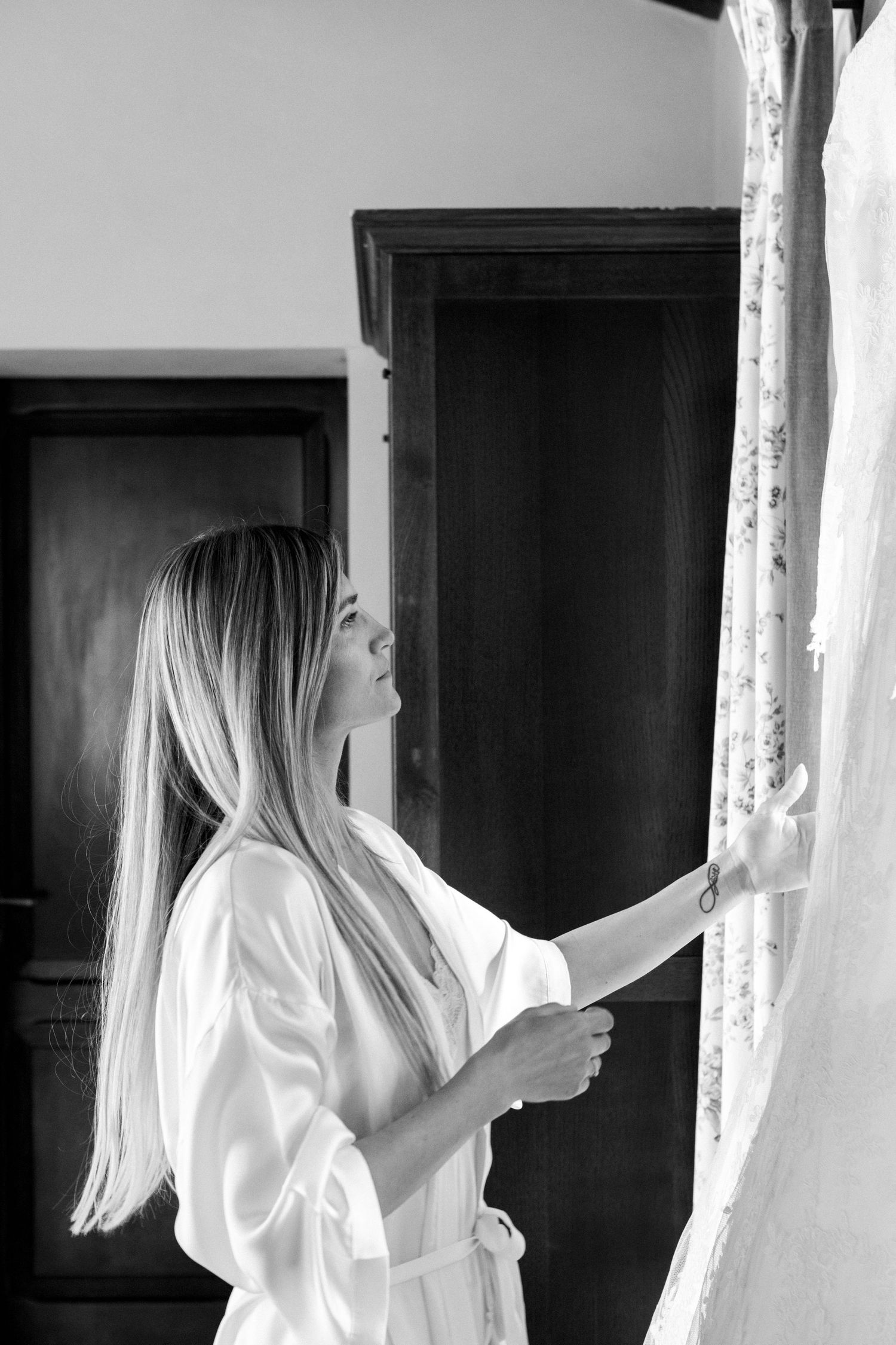 Black and white image of morning wedding preparations by window.