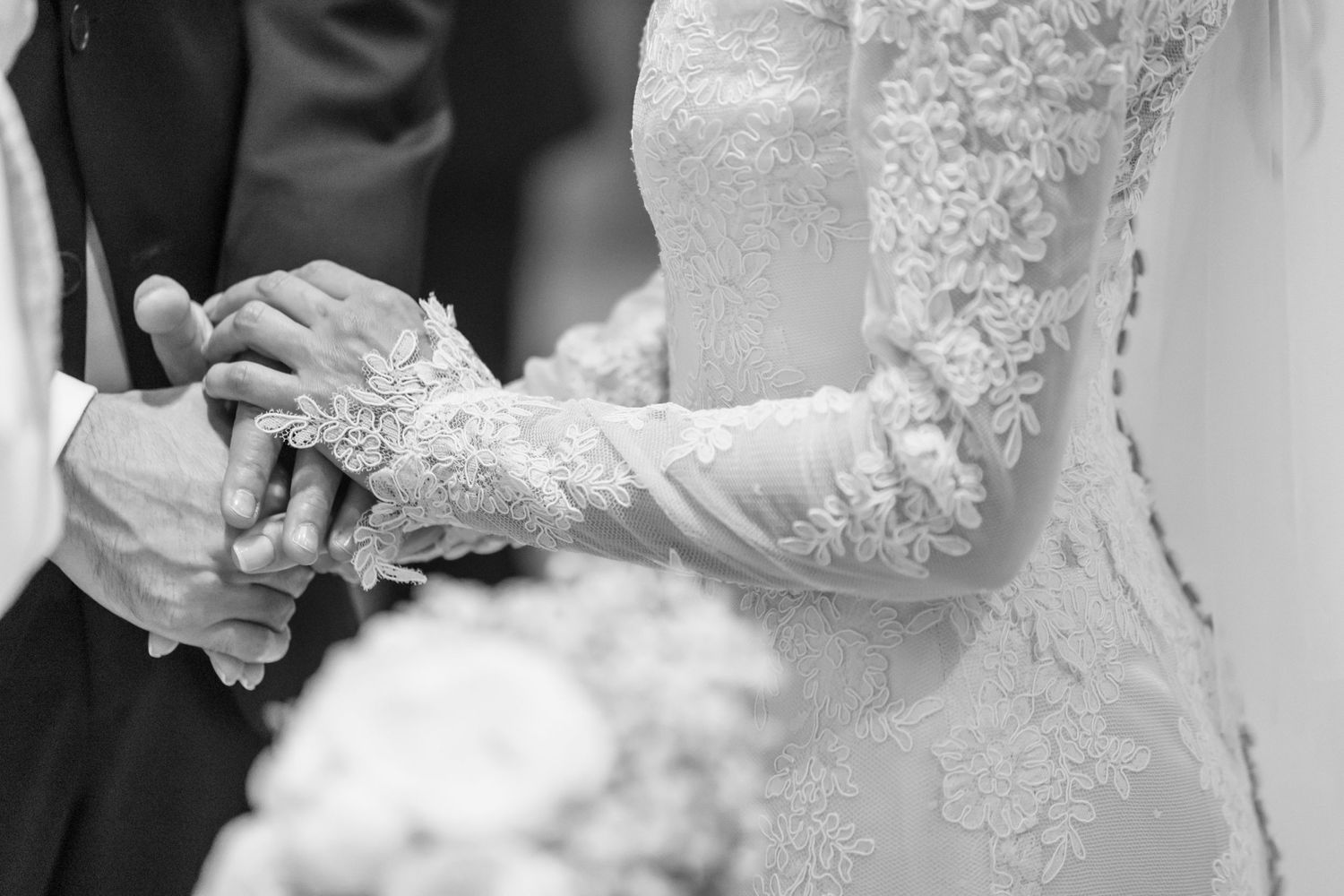 Close-up of lace wedding dress details during ring exchange ceremony.