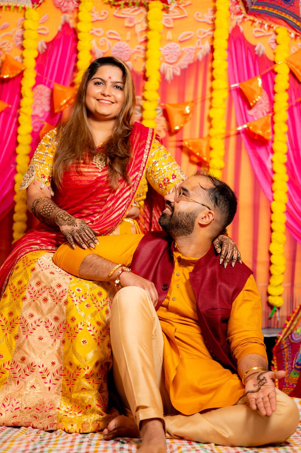 Vibrant Indian wedding photoshoot with traditional yellow and red decor and outfits.