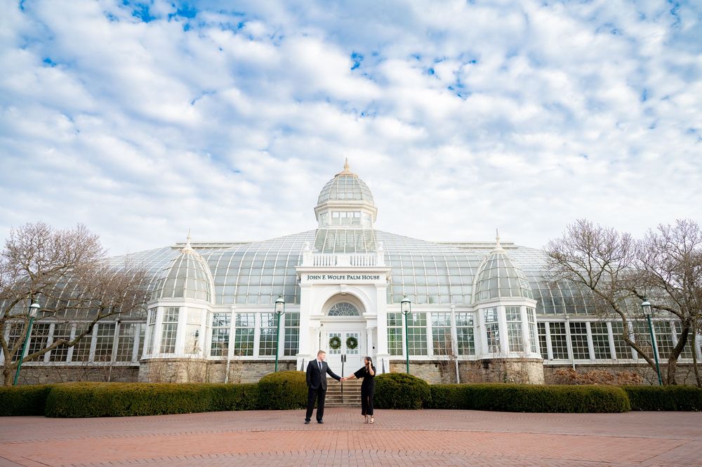 Panoramic view of a grand Victorian-style conservatory building with glass dome under cloudy skies.