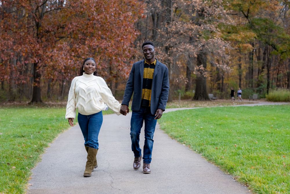 Couple walking together on a path surrounded by autumn foliage.