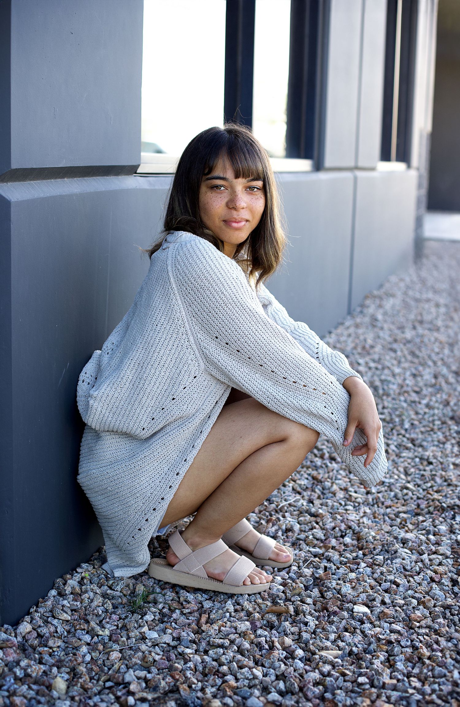 Artistic portrait series showing a soft knit sweater against a modern architectural background.