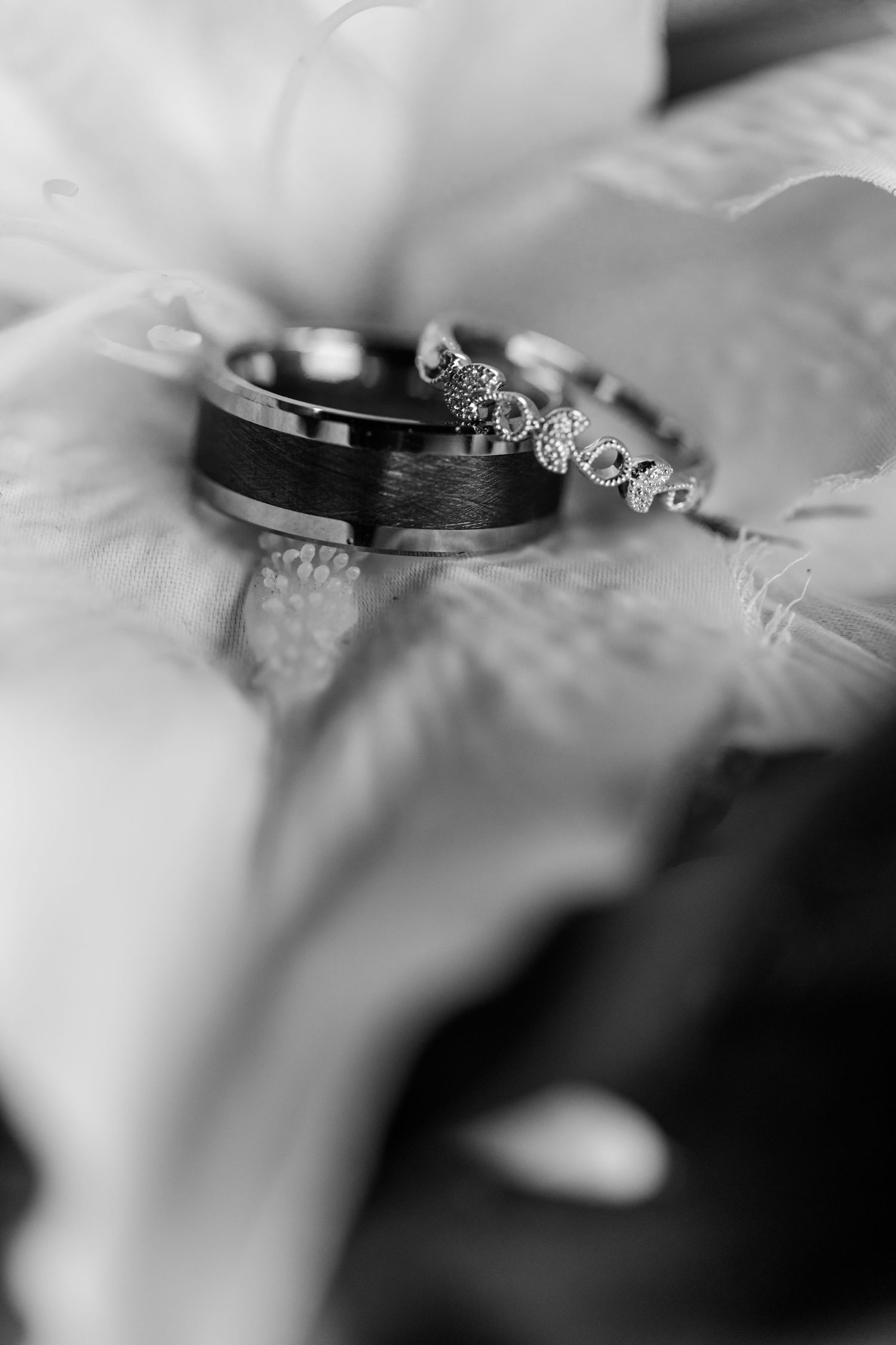 Wedding rings photographed in black and white with soft focus and dramatic lighting.