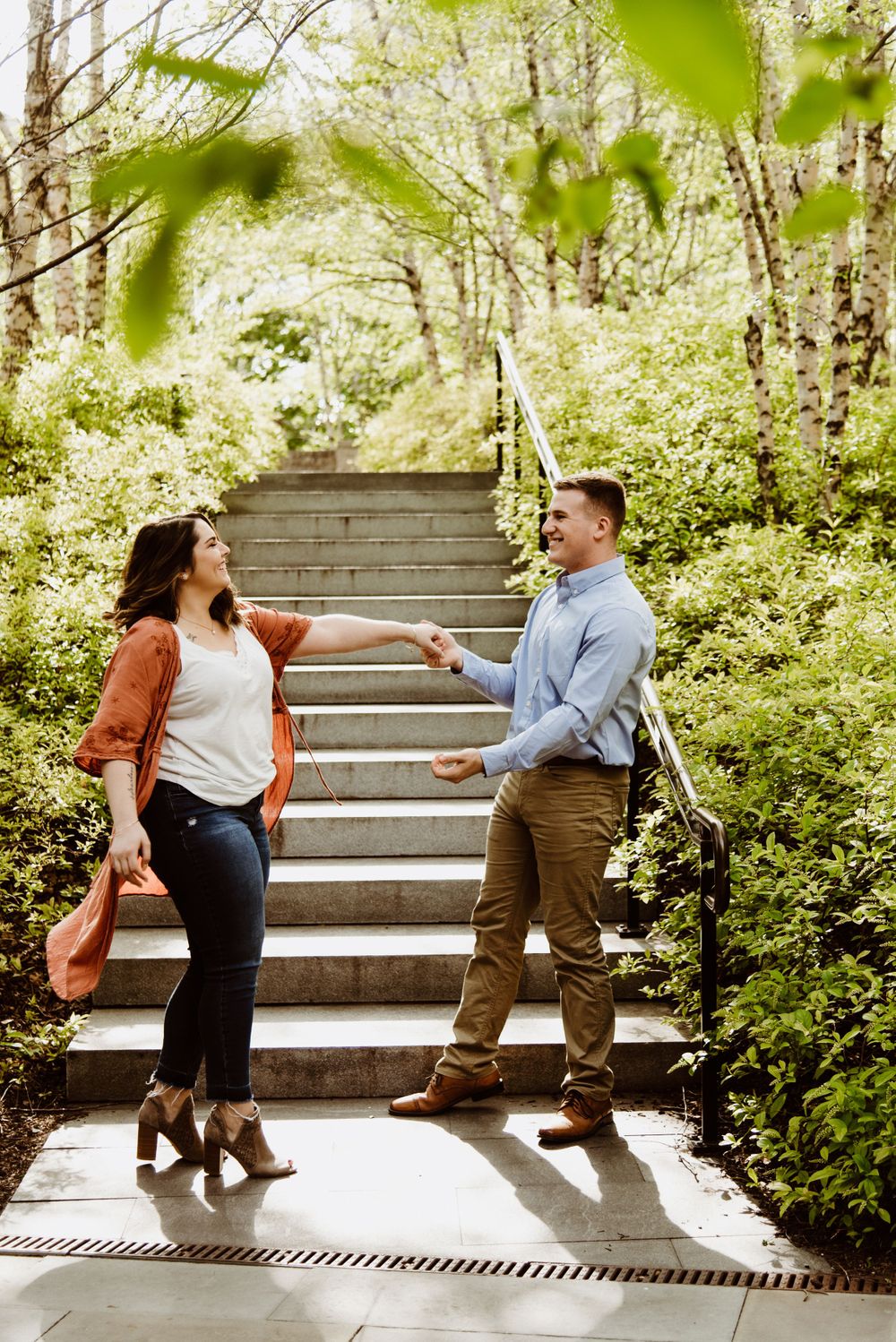 Playful sequence of a couple dancing and posing on stone steps surrounded by lush greenery.