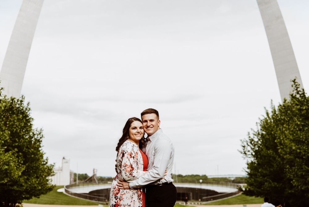 Couple shares romantic moment with St. Louis Gateway Arch in background.