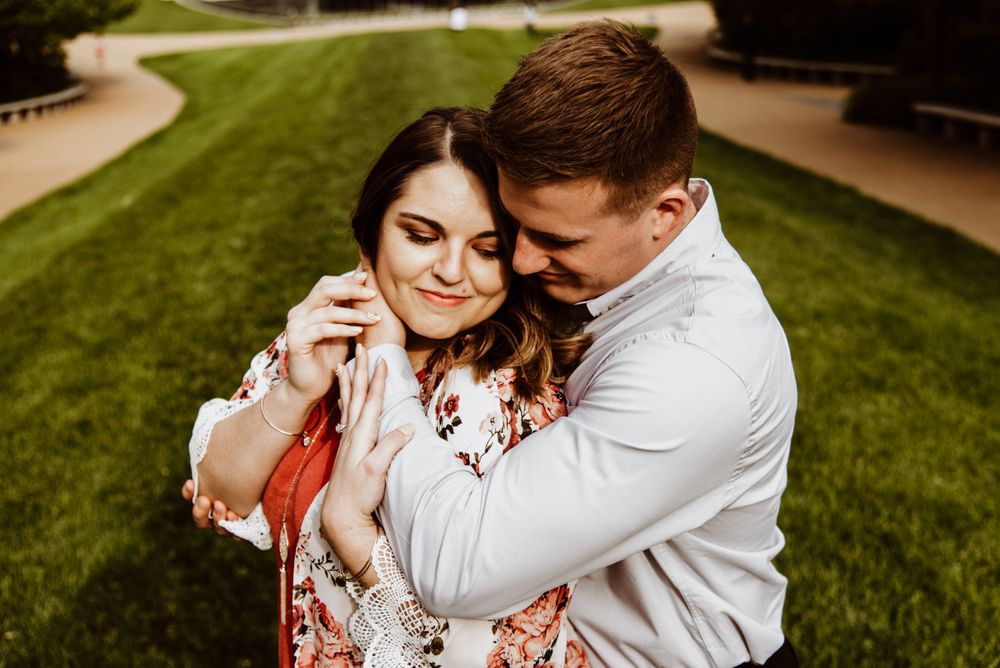 Intimate embrace captured against Gateway Arch backdrop during outdoor photoshoot.