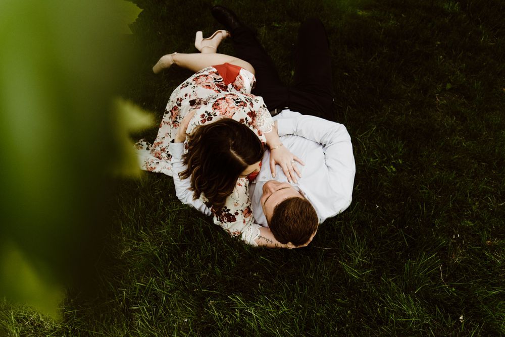 Overhead view of couple embracing on dark grass during outdoor photoshoot.