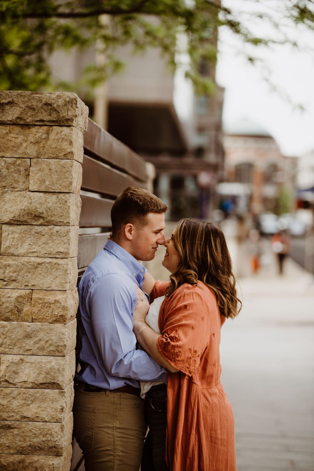 A romantic couple shares a tender moment against a stone wall backdrop.