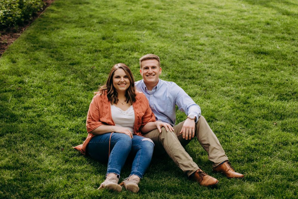 A couple relaxes together on lush green grass during a sunny day.