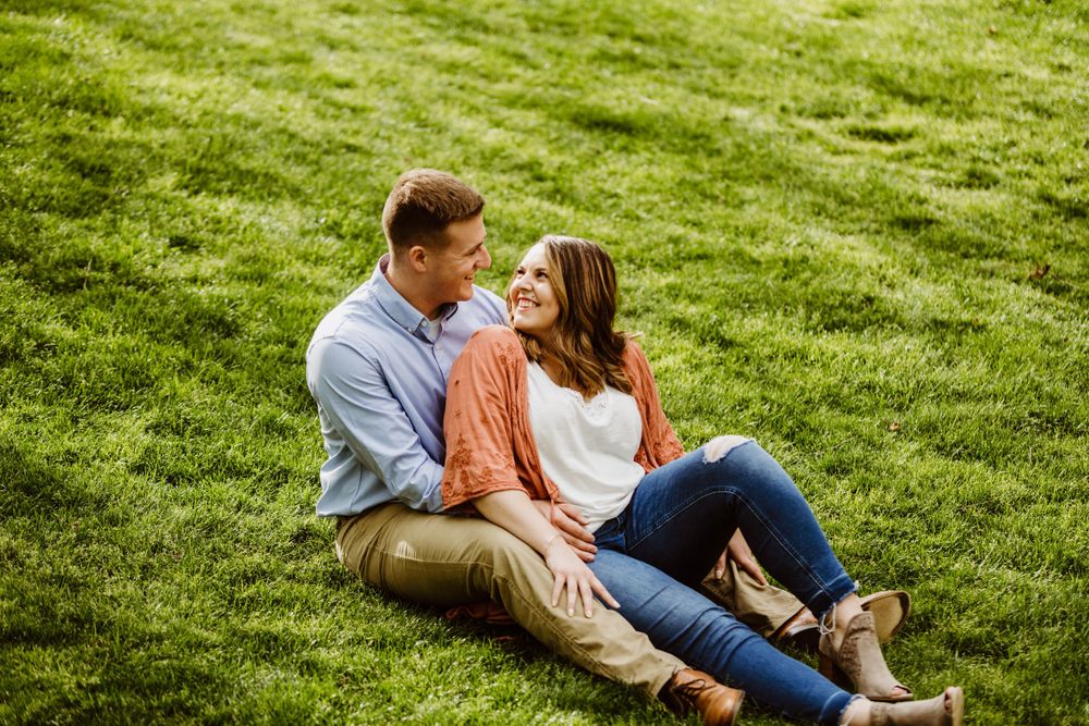 Two people share an intimate moment while lying on bright green grass.
