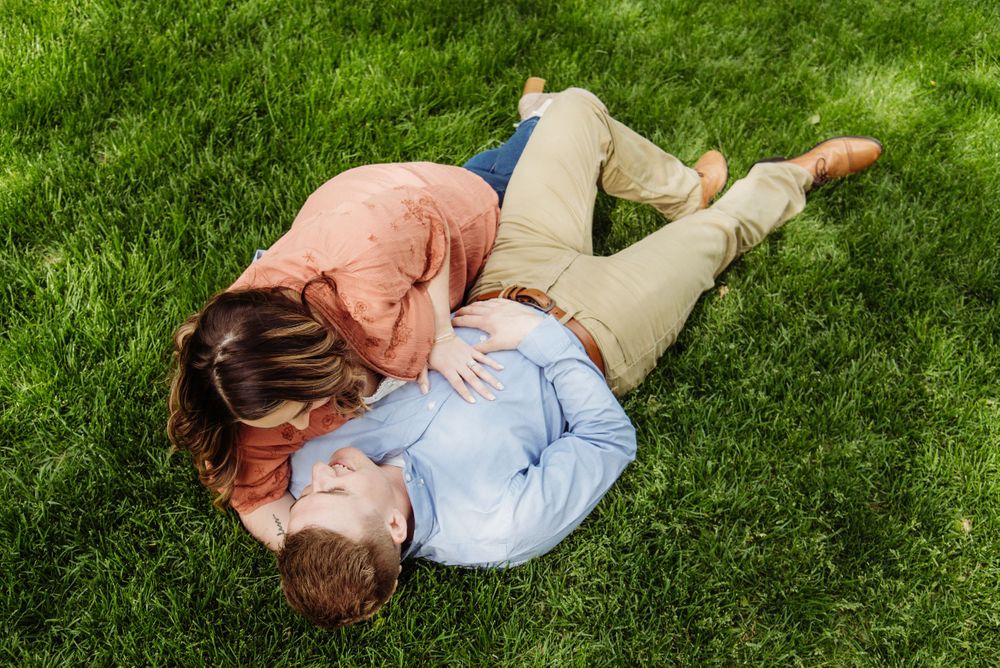Couple lying together on vibrant green grass during a romantic photoshoot.