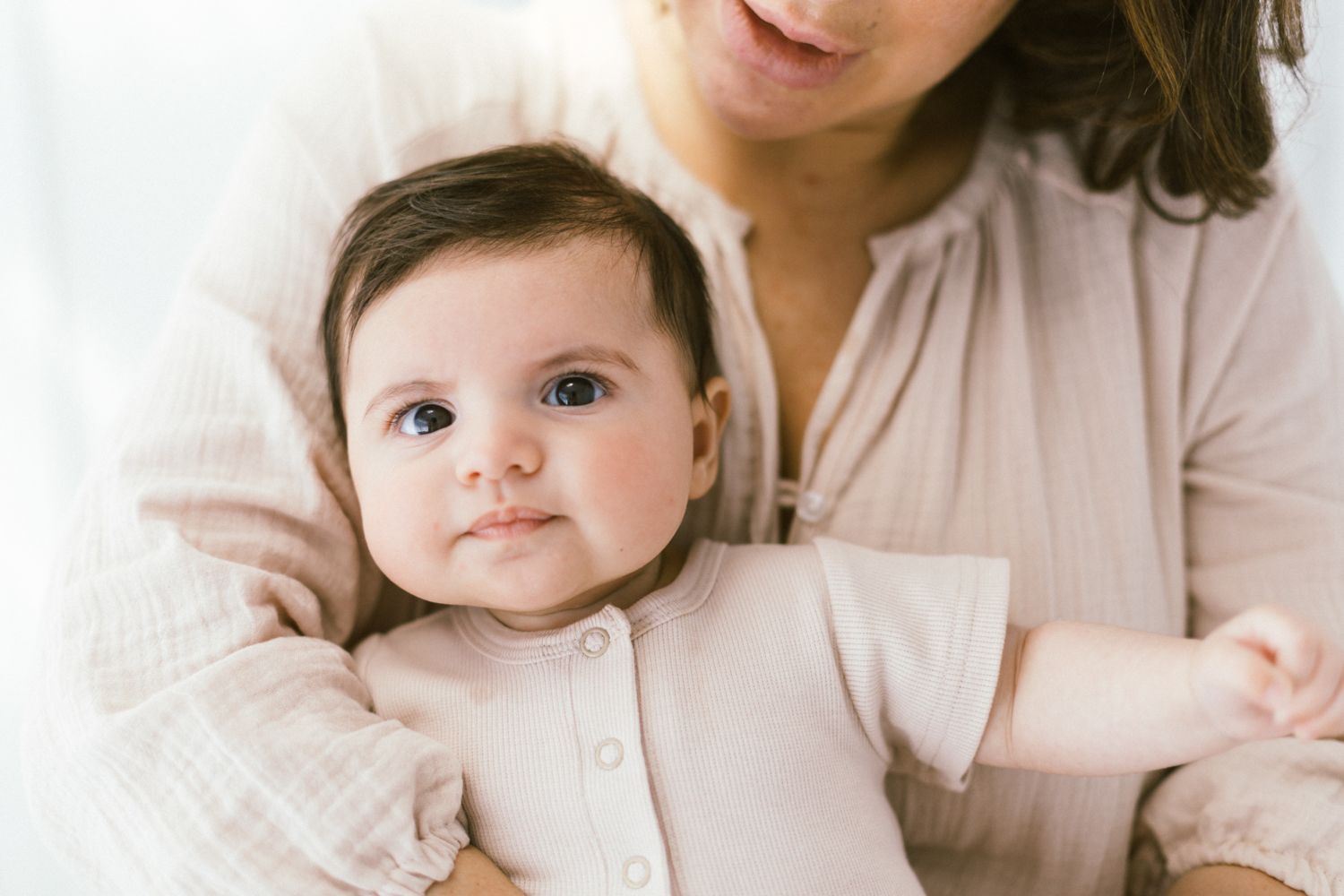 Close-up shots capturing sweet interactions in matching light pink outfits.