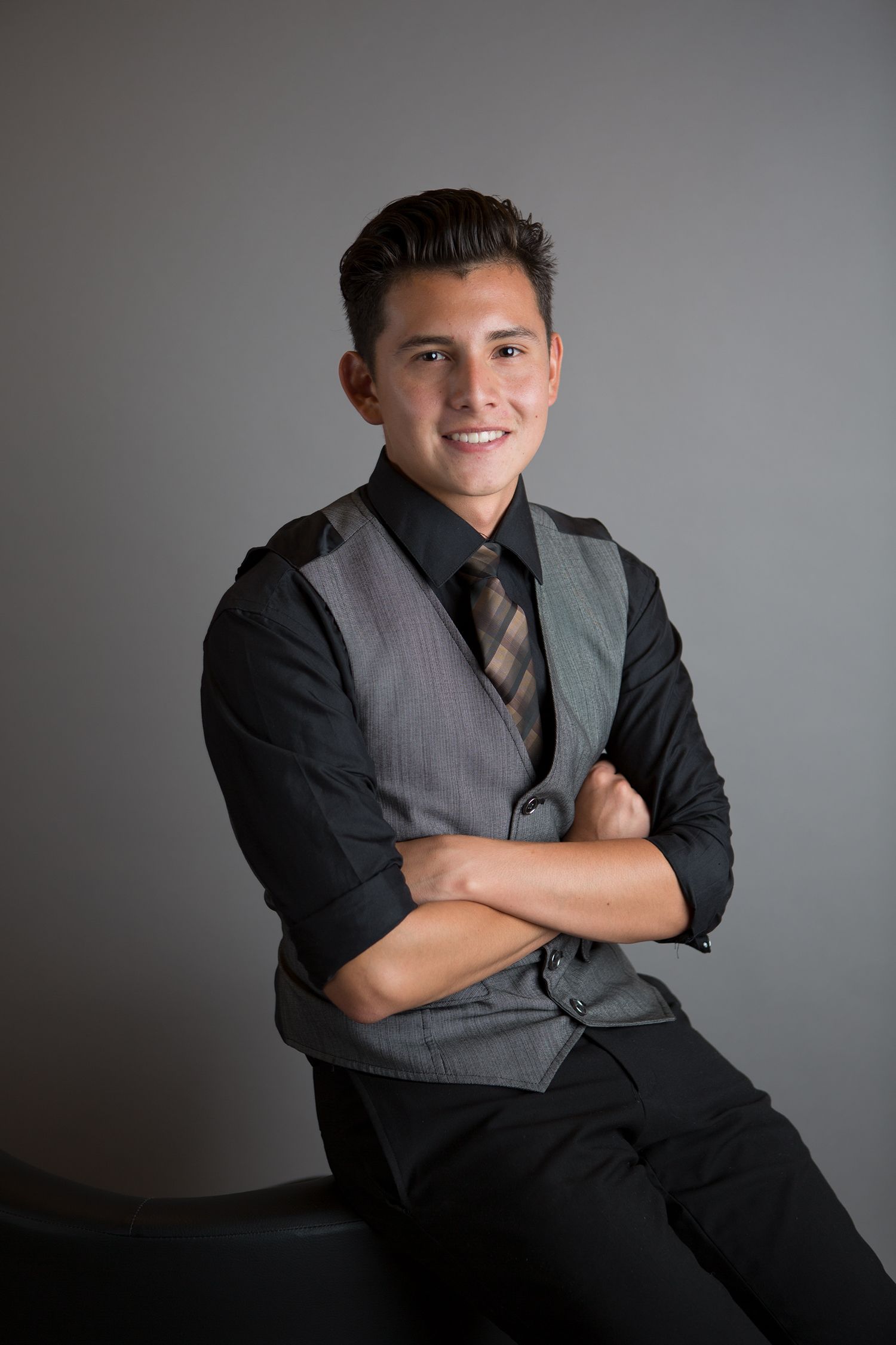 Professional portrait of person in gray vest and black shirt.