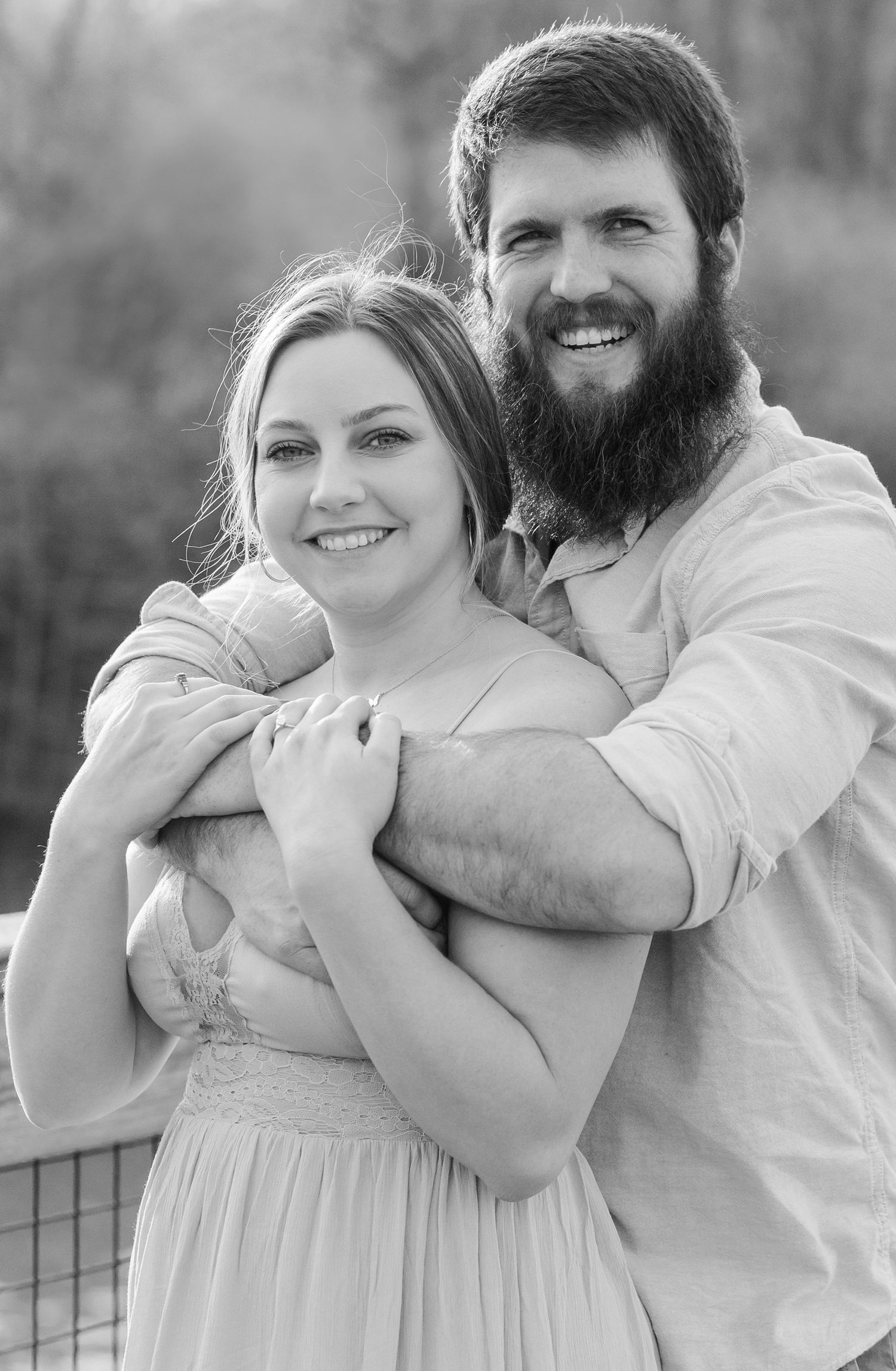 Black and white portrait of a couple sharing a playful moment outdoors.