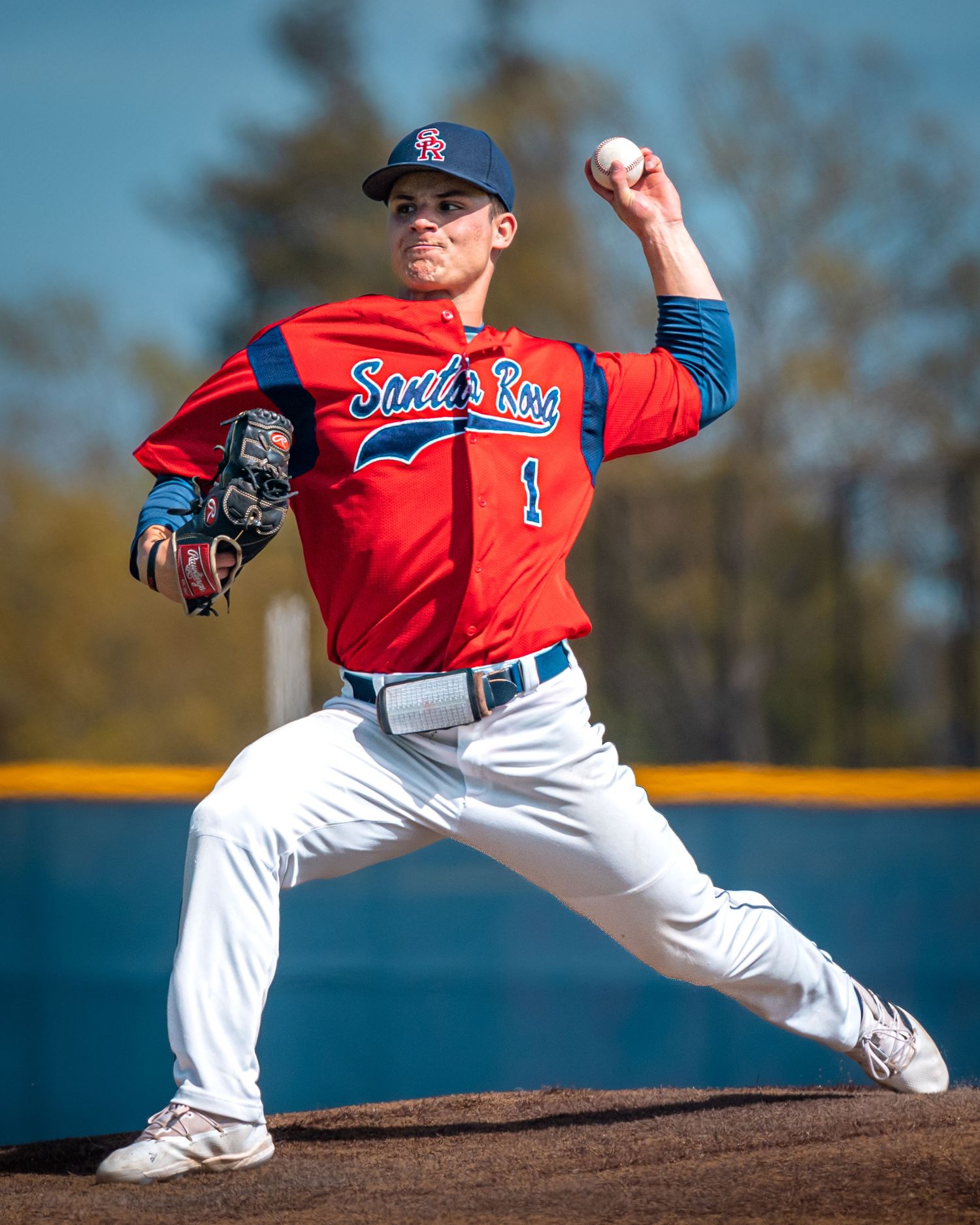 Baseball pitcher in red uniform mid-delivery on the pitcher's mound.