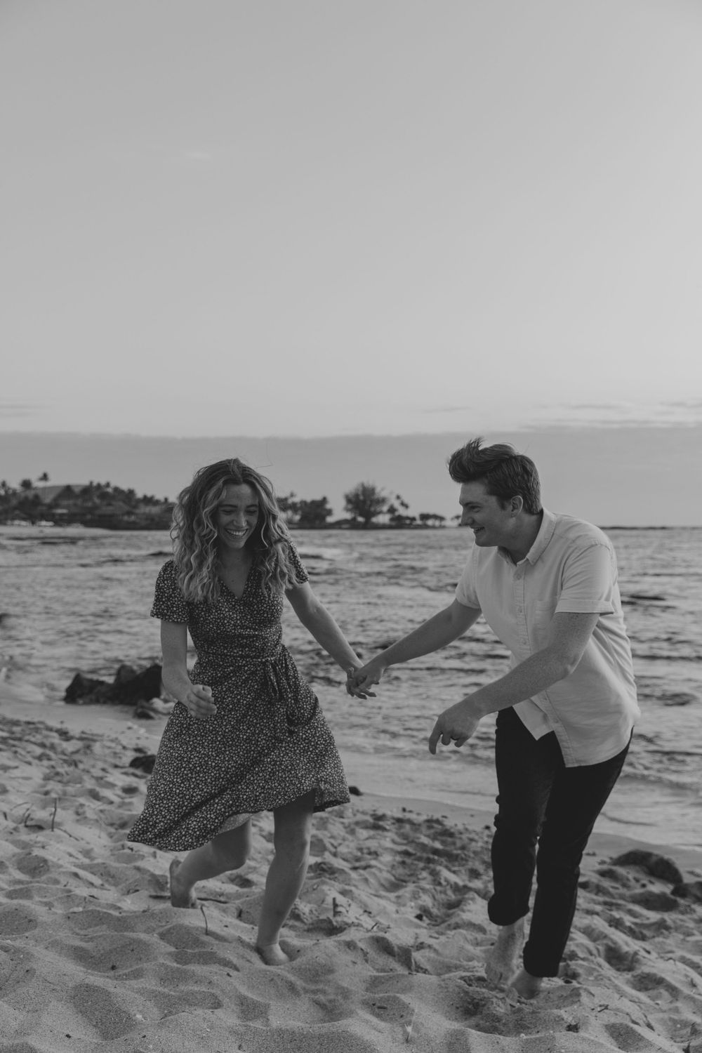 A couple enjoys a playful moment together on a sandy beach.