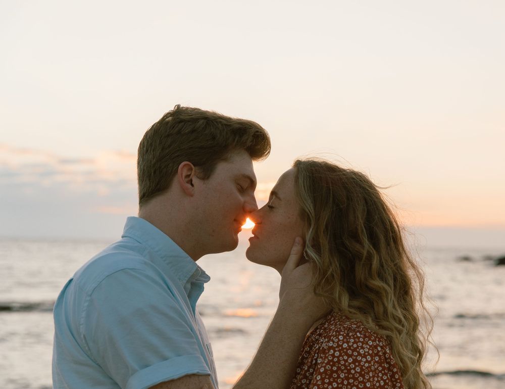 Intimate close-up of couple sharing a tender moment at sunset by the ocean.