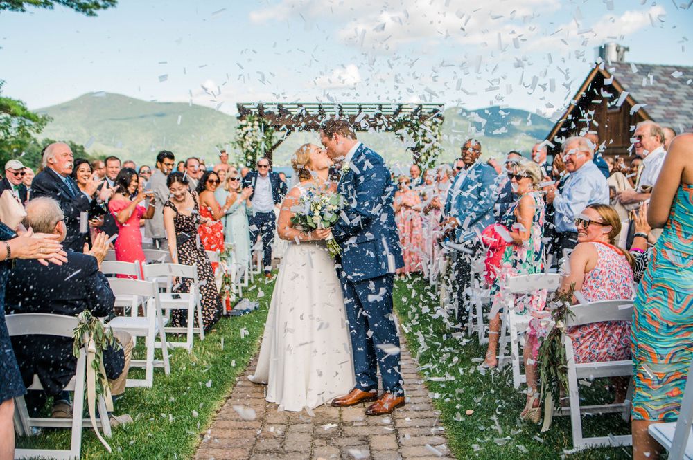 bride and groom kissing in the middle of the aisle surrounded by confetti at Blue Water Manor in Lake George, NY