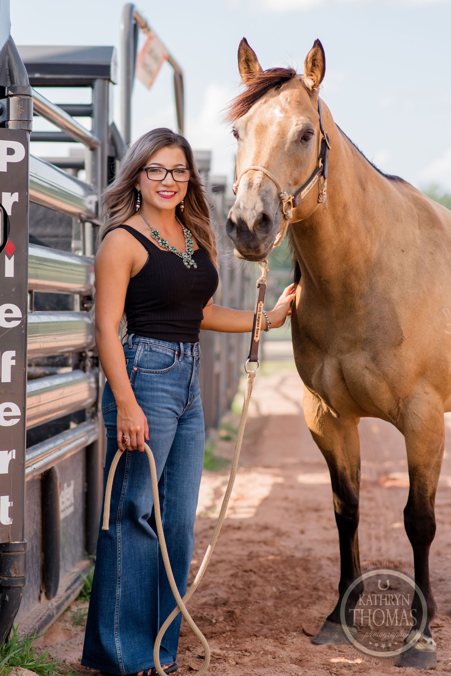 A beautiful palomino horse stands next to a metal gate at an outdoor equestrian facility.