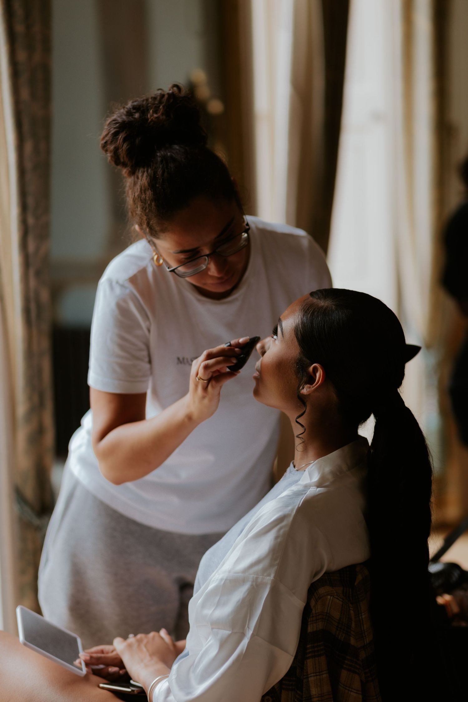 Makeup artist applying cosmetics on a client's face during a professional beauty session.