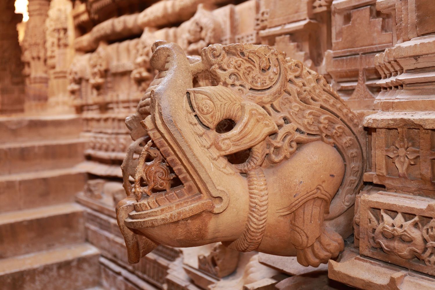 Detailed stone carving of mythical creature on temple steps in Rajasthan.