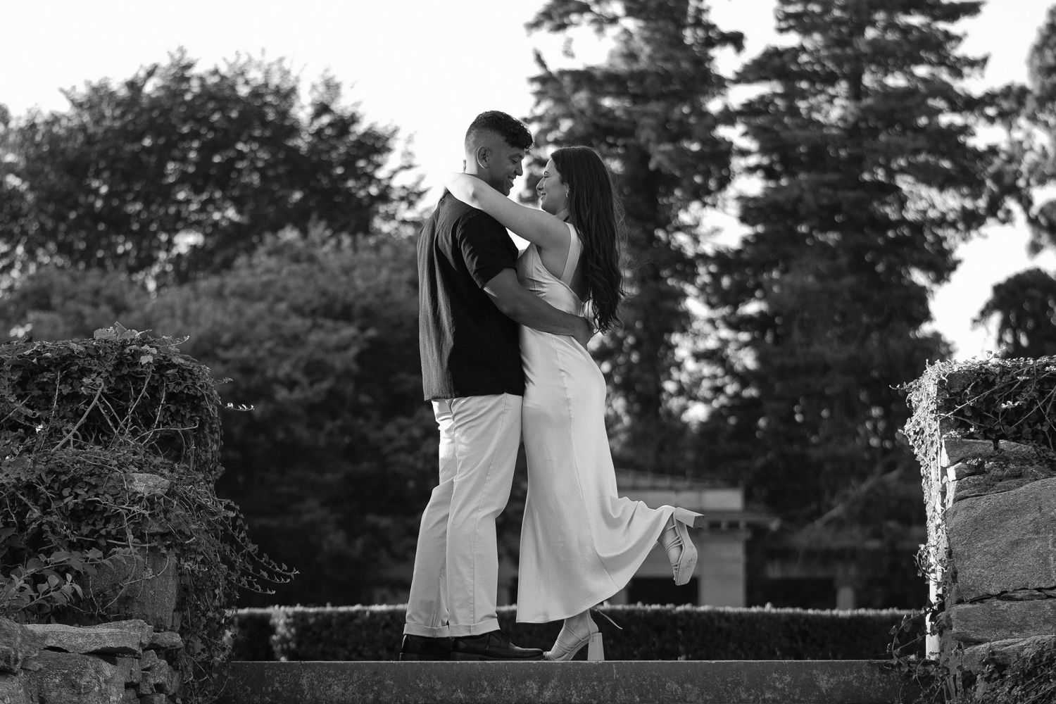 Black and white photo of a couple dancing on garden steps.