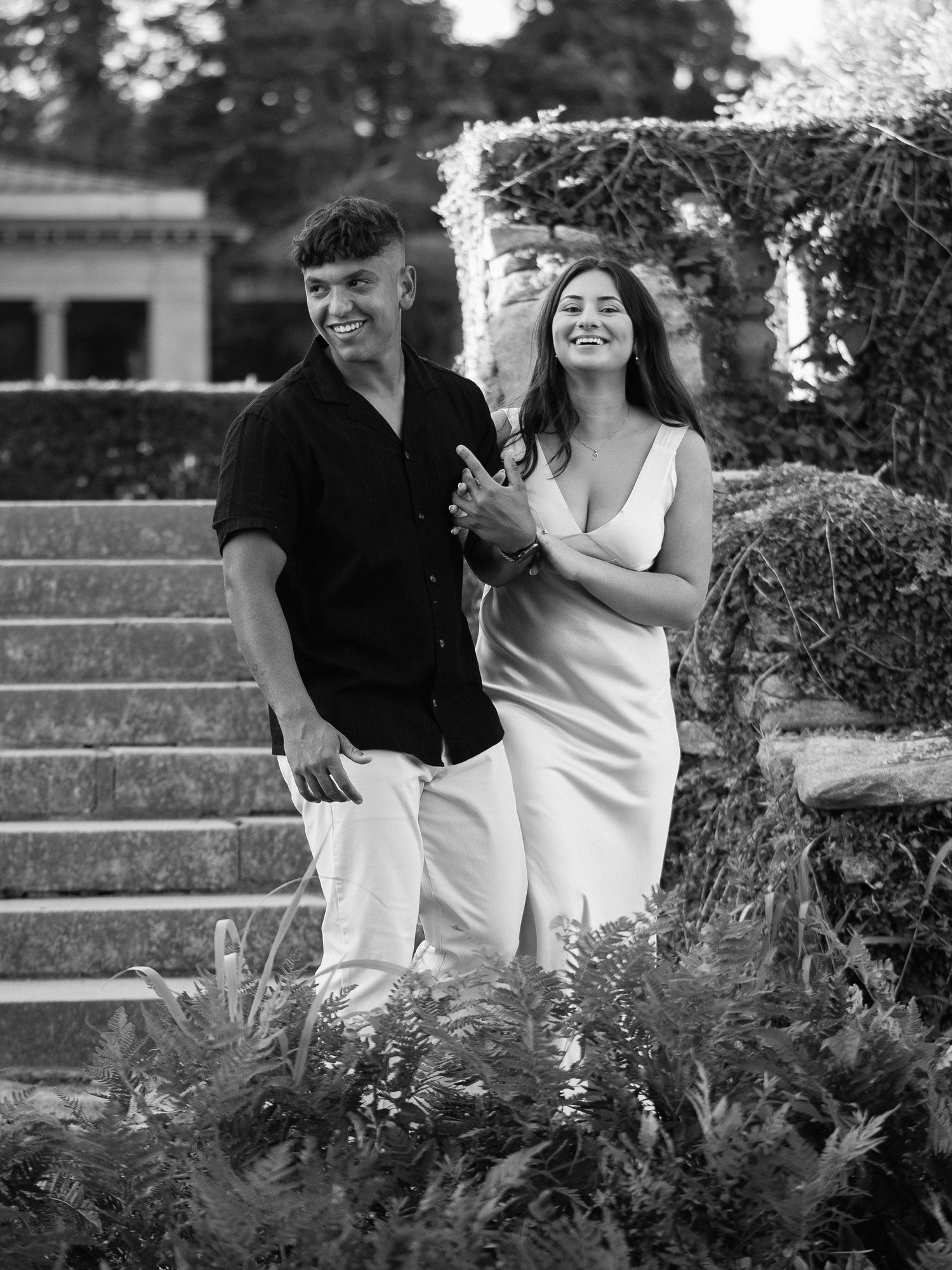 Candid moment captured of couple laughing together on garden steps.