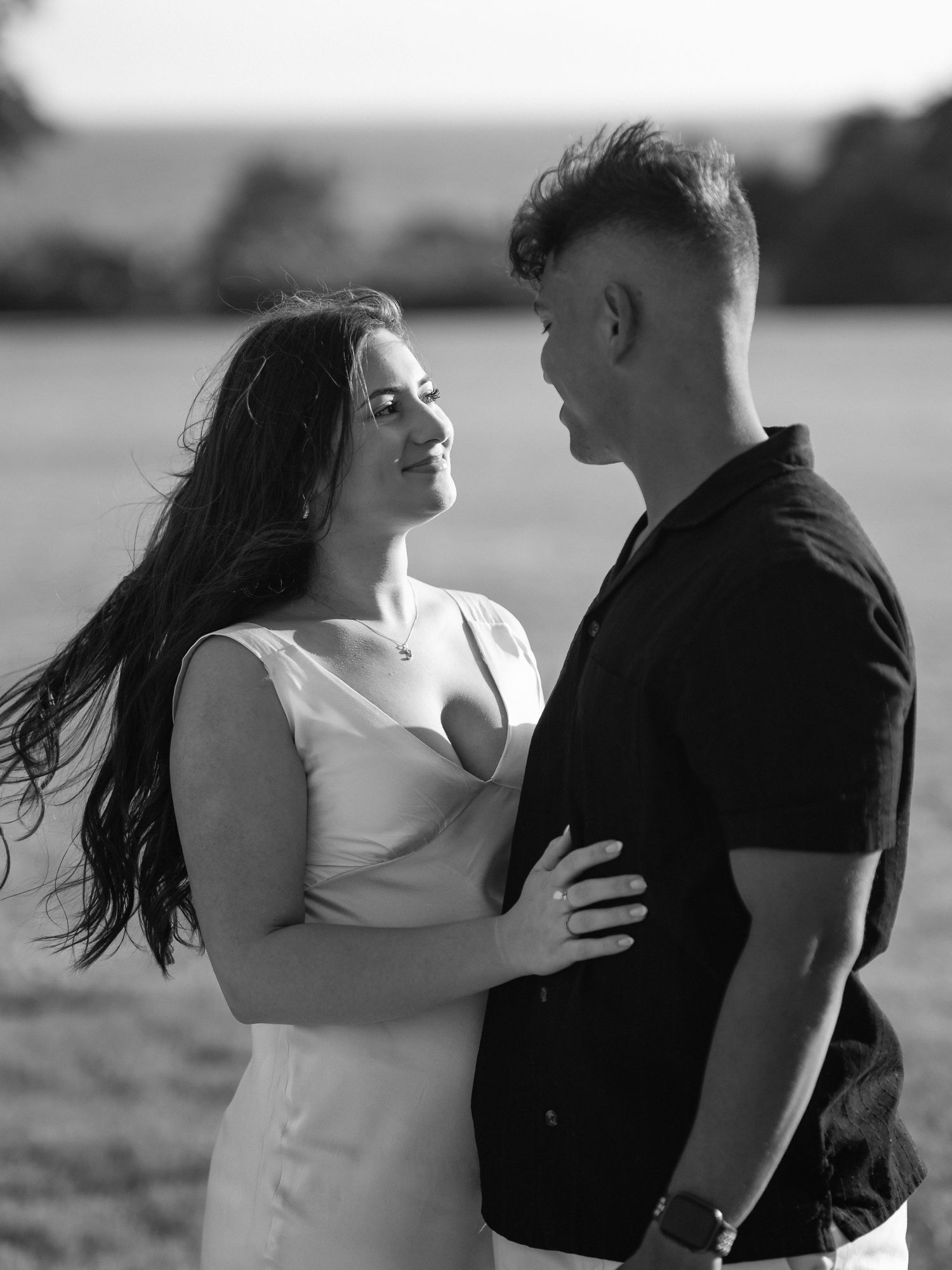Black and white photo of couple embracing in an outdoor setting.