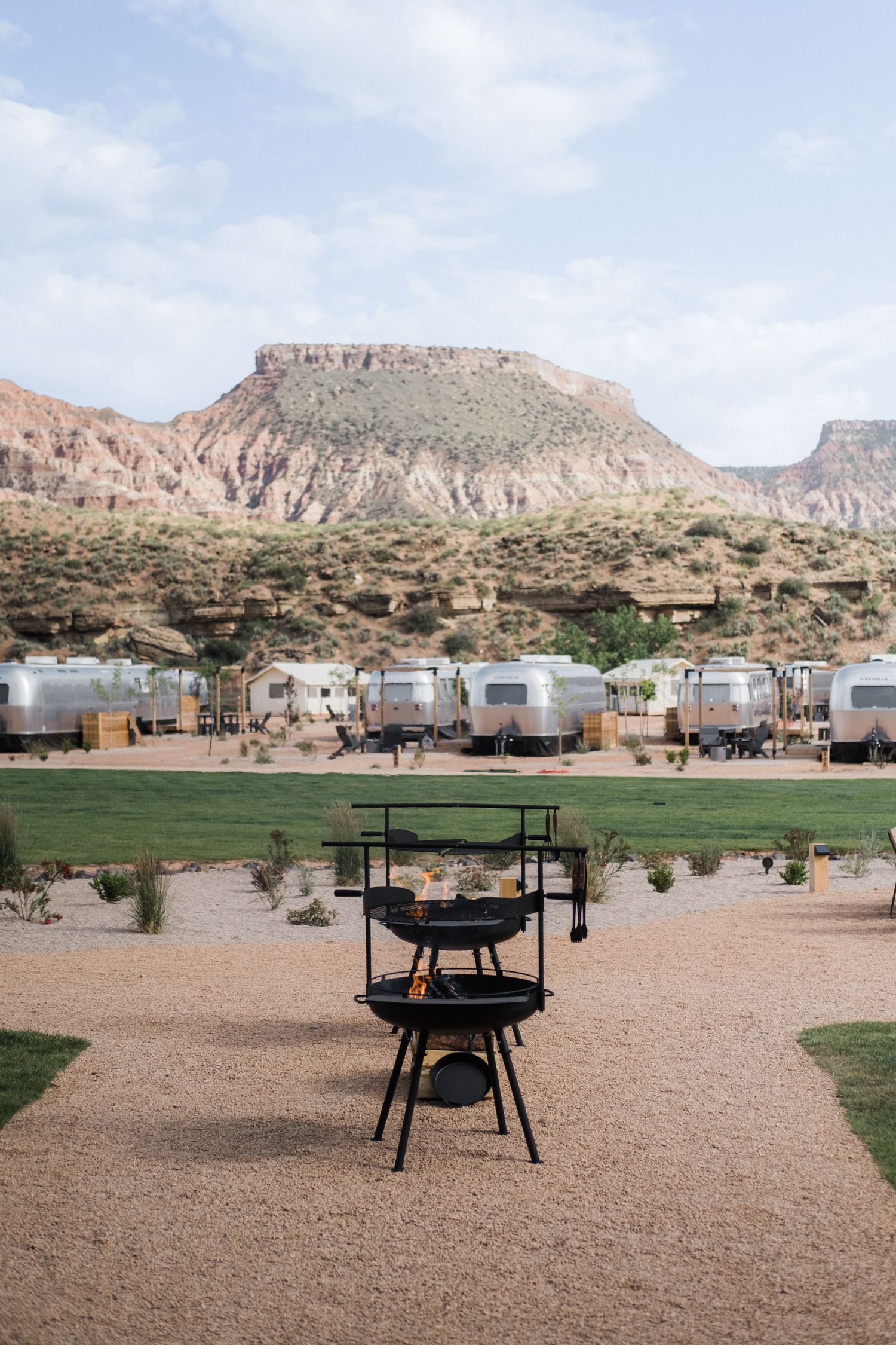 RV campground with fire pits set against dramatic desert cliffs and mesas.