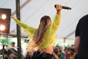 Performer in yellow top energetically singing on stage during concert.