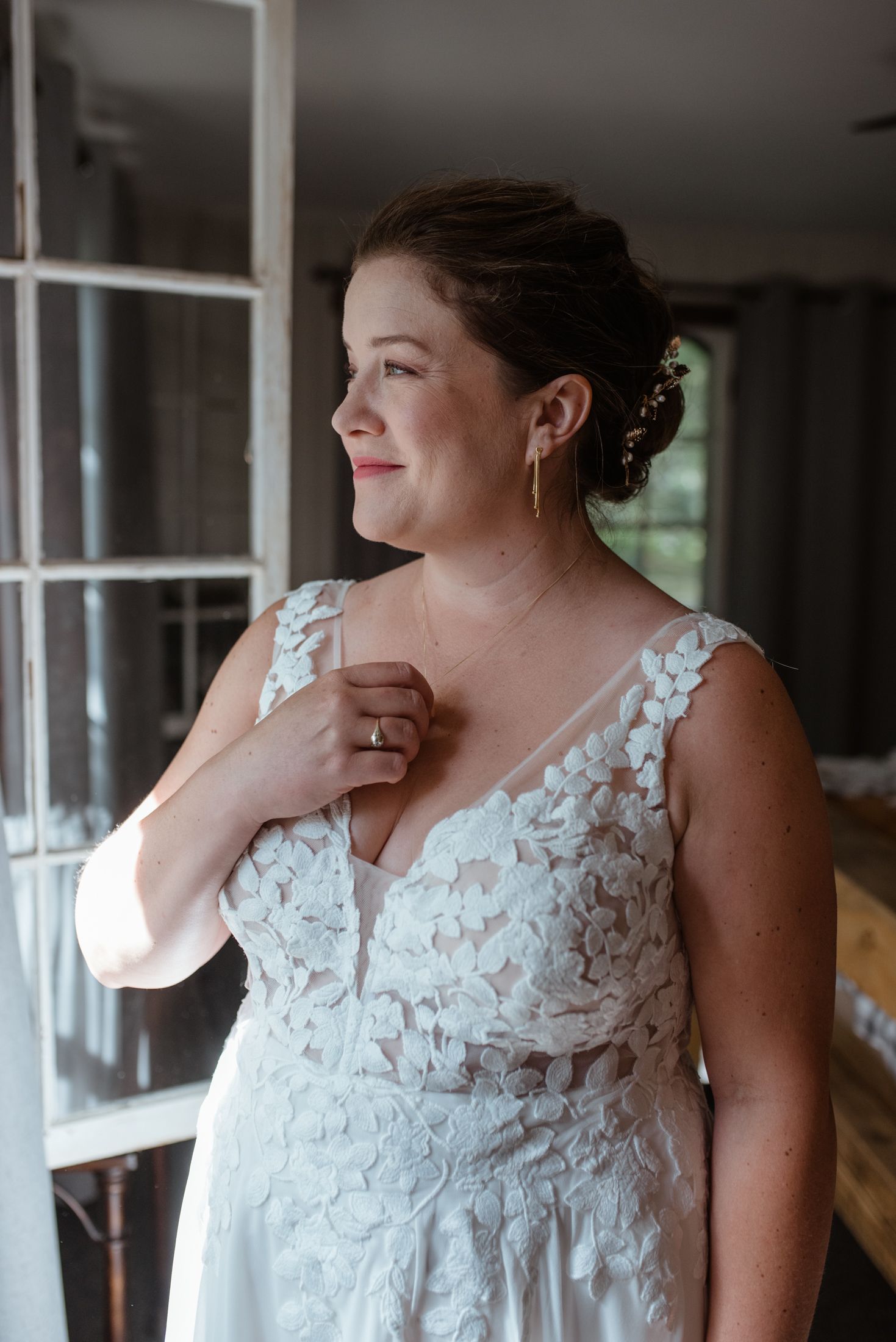 Close-up portrait showing intricate lace detail of a white wedding dress with elegant updo hairstyle.
